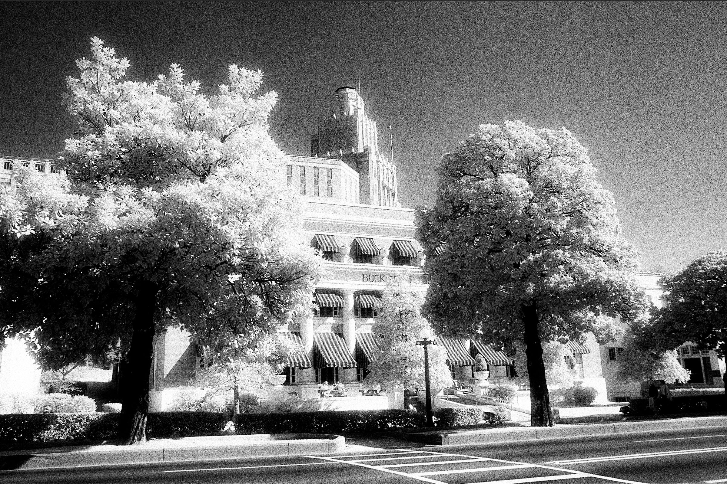 a black and white photo of a building with trees in front