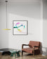abstract heart in pink, green, gold, teal, red on white background in black frame on light gray wall in modern residential sitting room