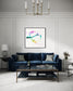 abstract heart in pink, green, gold, teal, red on white background in black frame with white matte on light gray wall with blue sofa in modern living room