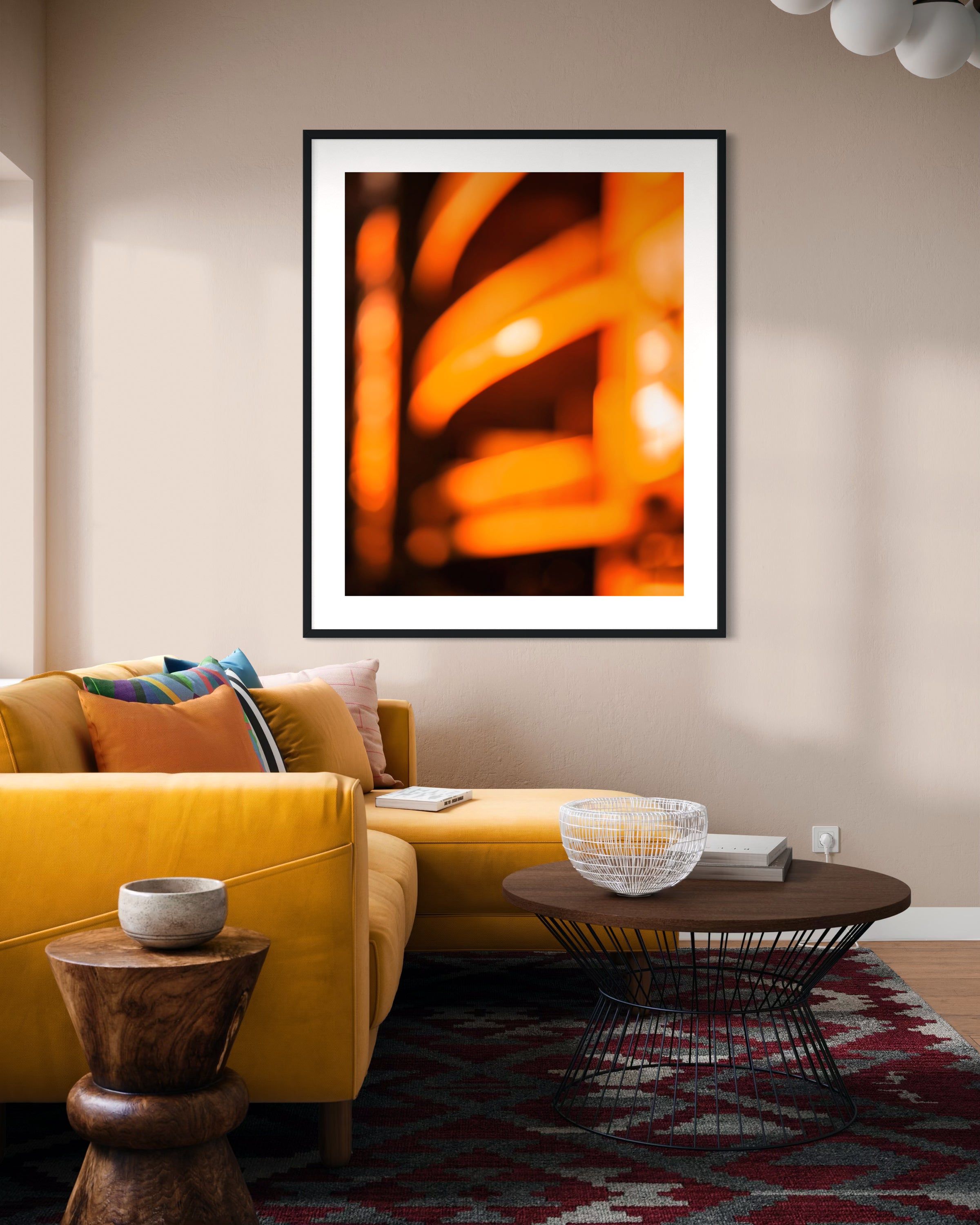 photo of abstract orange blurred lines in black frame with white matte on tan wall in living room with yellow couch and wooden coffee table