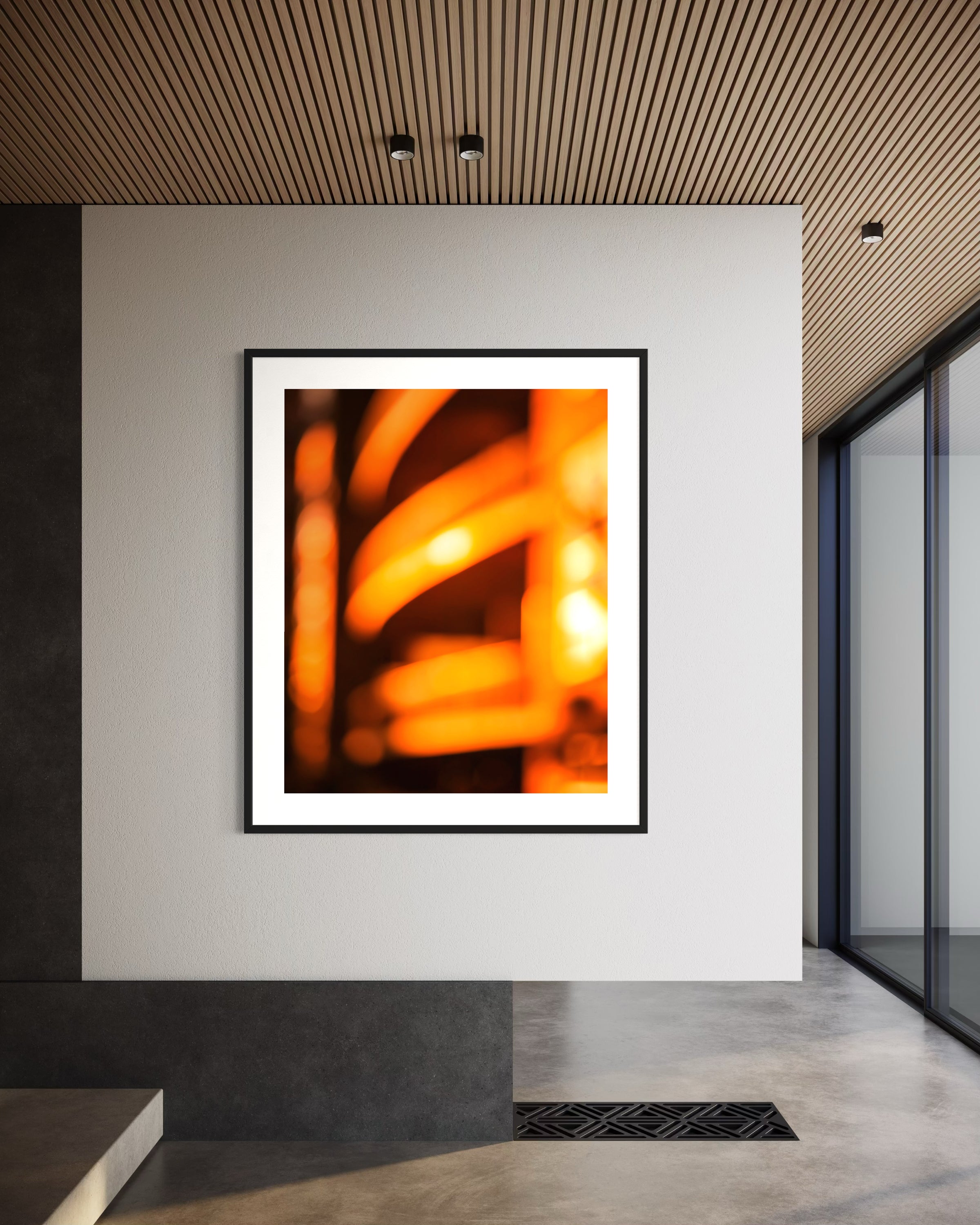 photo of abstract orange blurred lines in black frame with white matte on white wall in minimalist office space with concrete floors