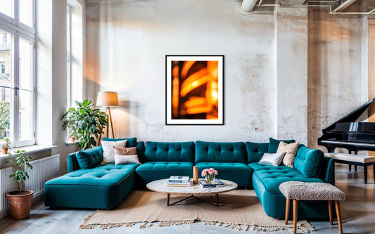photo of abstract orange blurred lines in black frame with white matte in urban loft living room large teal couch and concrete walls