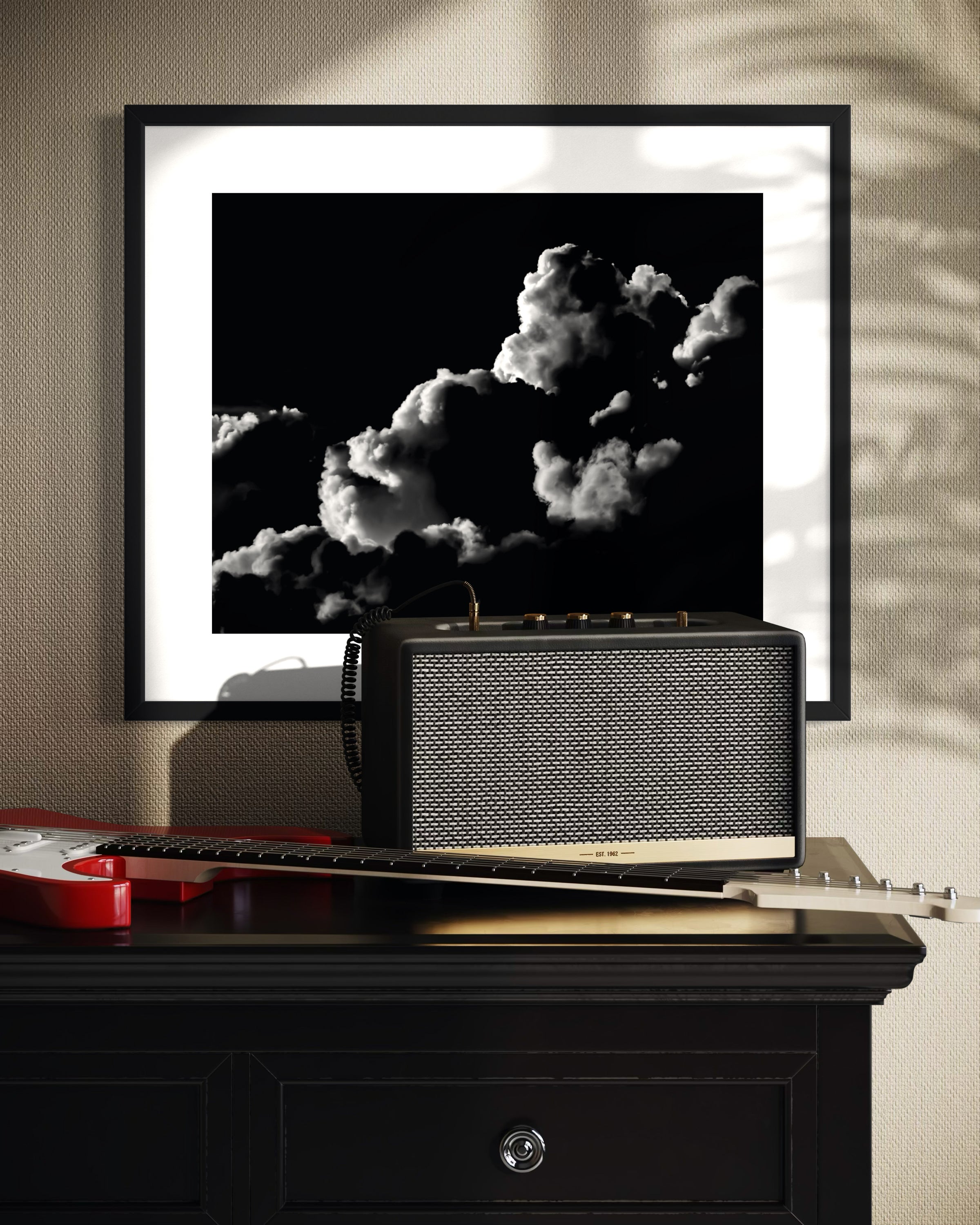 Framed black and white photograph of clouds above a vintage radio on a wooden surface.