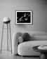 black and white photo of clouds, one looks like a dog's head in profile in black frame with white matte on off white wall in modern minimalist living room with gray couch