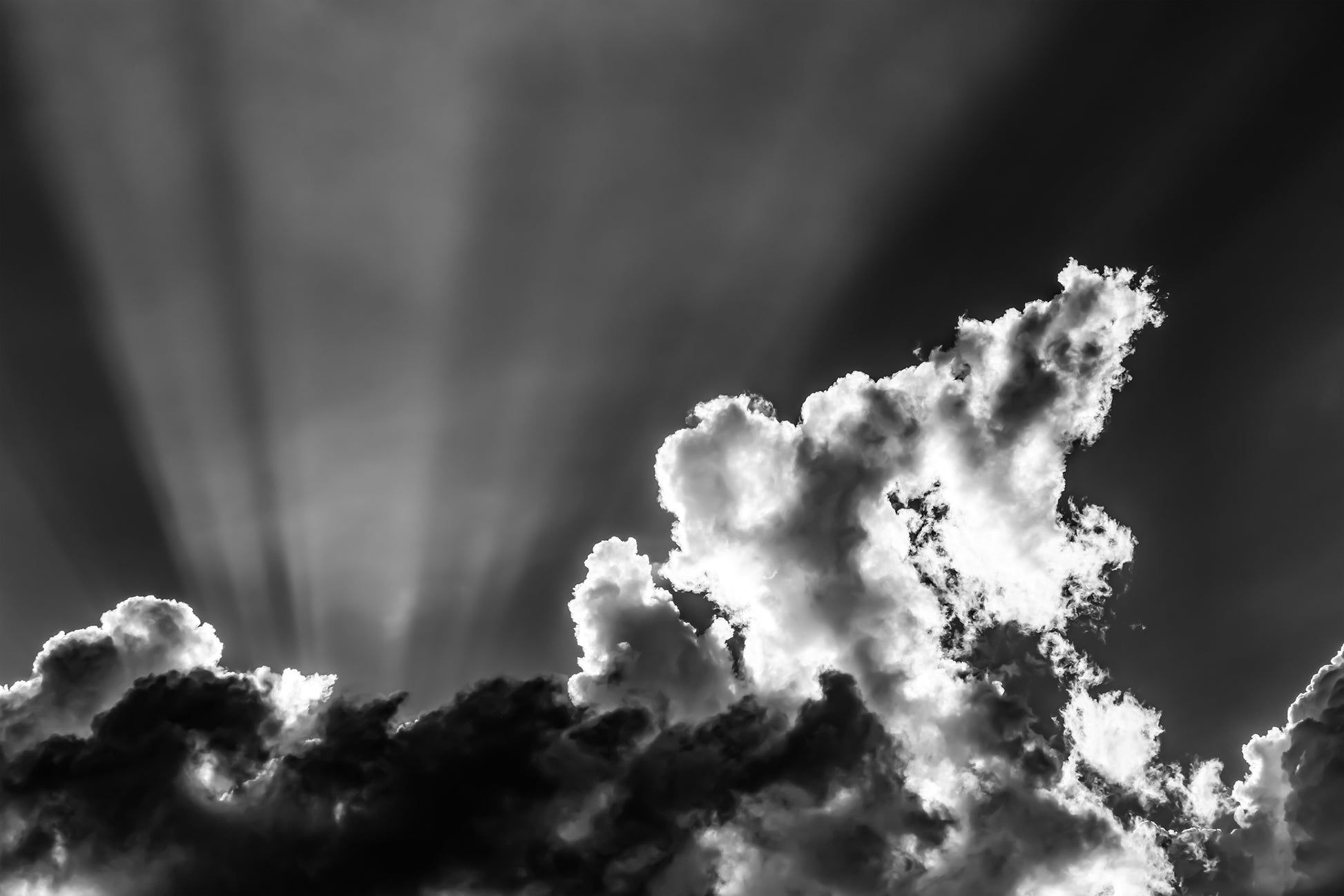 black and white photo of dramatic sky with some clouds and rays of light