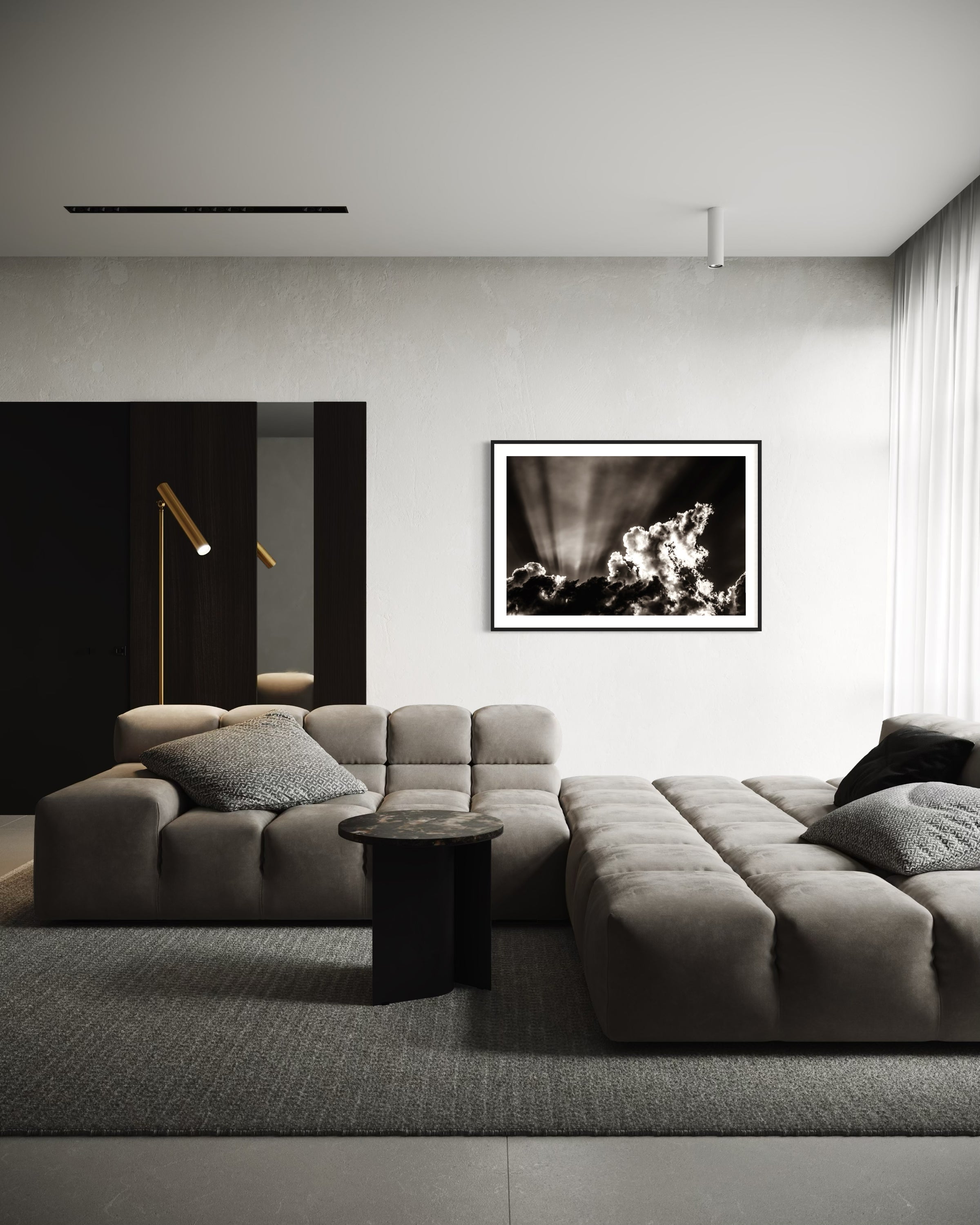black and white photo of dramatic sky with some clouds and rays of light  in black frame with white matte on white wall in modern living room with gray couches and rug