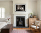black and white photo of dramatic sky with some clouds and rays of light in black frame with white matte on off white wall above fireplace in rustic bedroom 