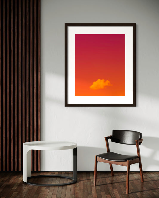 photo of single cloud, orange and magenta background in black frame with white matte on white wall in seating area