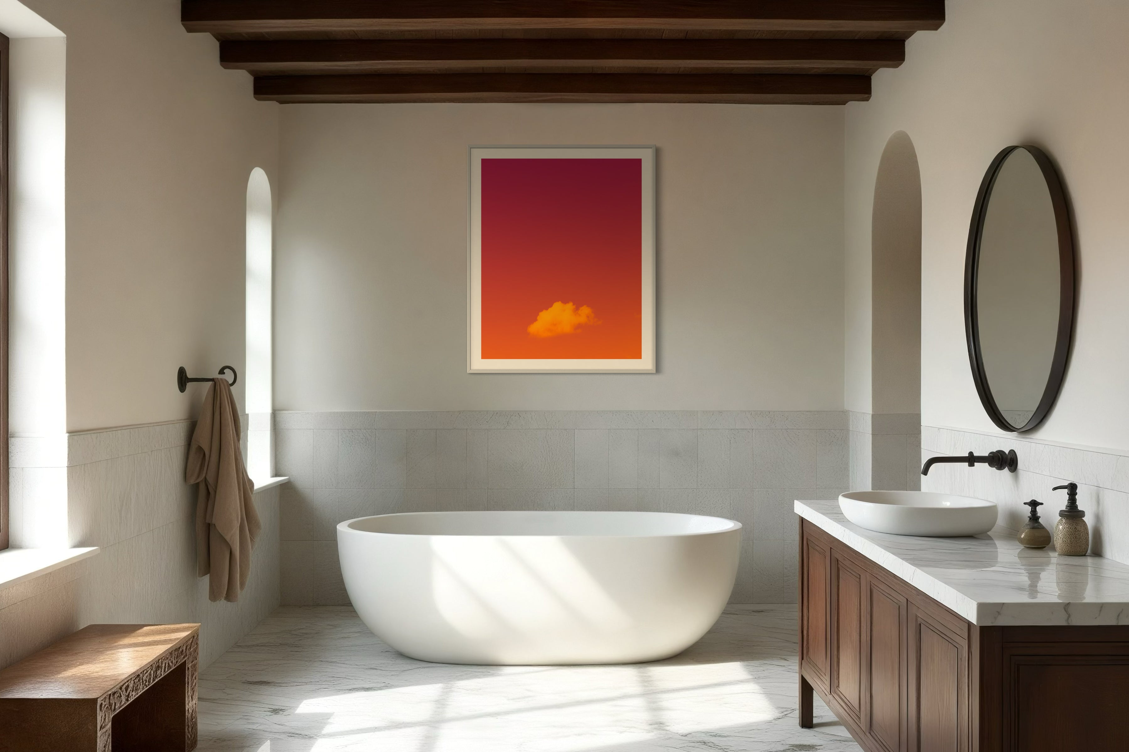 warm tone photo of single cloud in gray frame with white matte on tan wall in minimalist residential bathroom with free standing oval bathtub 