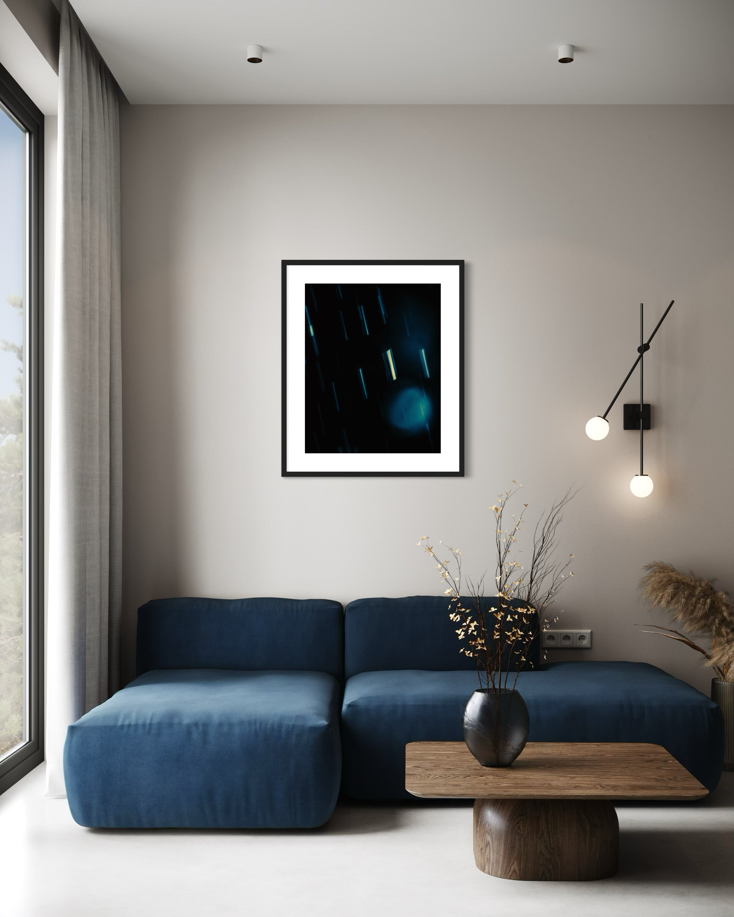 close up cool toned photo of streaks of rain in black frame with white matte on light warm gray wall with sconce on the side above blue couch with wooden coffee table in front