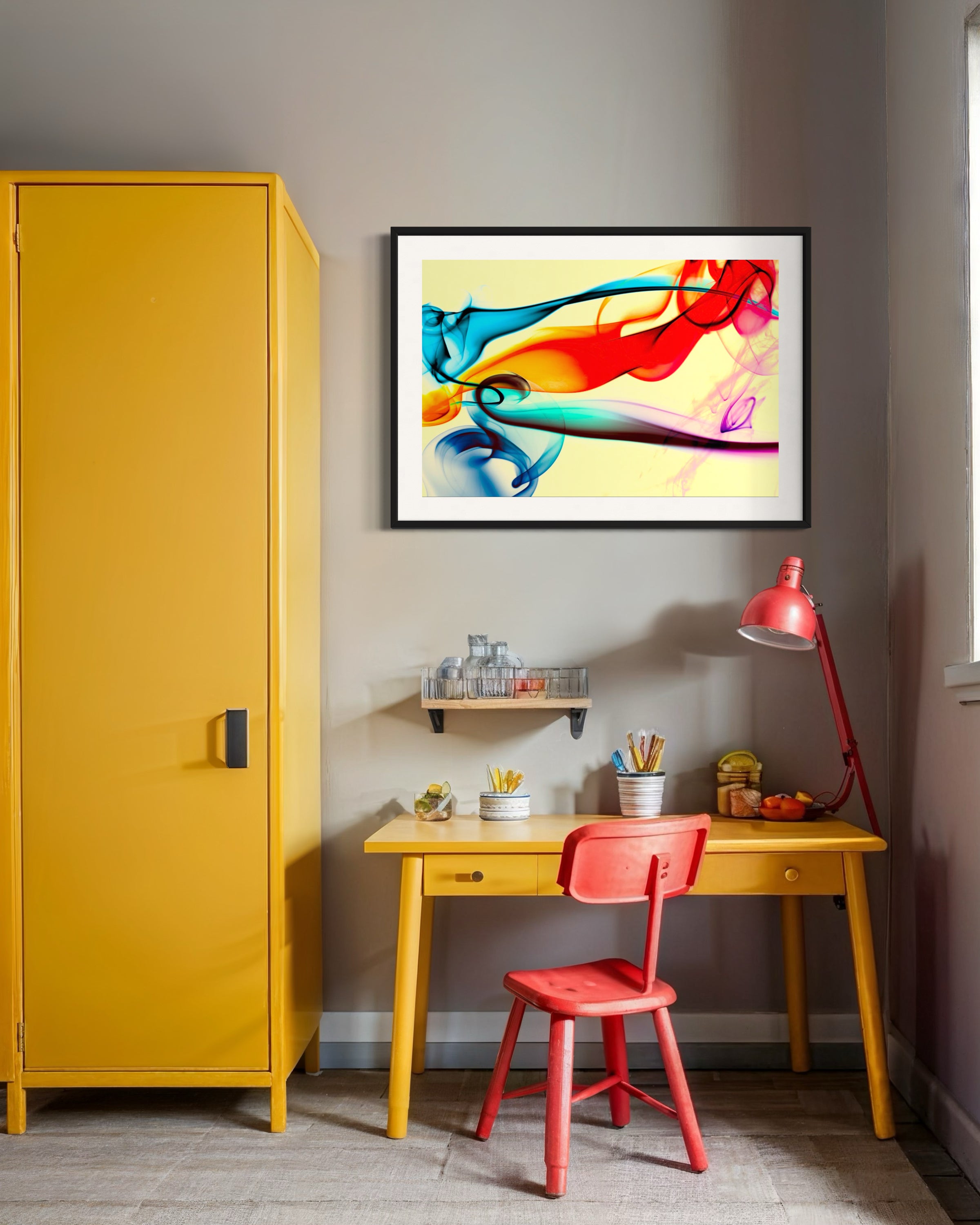 Yellow cabinet, red chair, and desk with colorful abstract art on a gray wall.