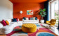 swirls of blue, yellow, orange, teal, purple and red on light yellow background in black frame with white matte on orange wall in very colorful living room 