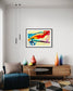 swirls of blue, yellow, orange, teal, purple and red on light yellow background in black frame with off white matte on white wall in modern sitting area