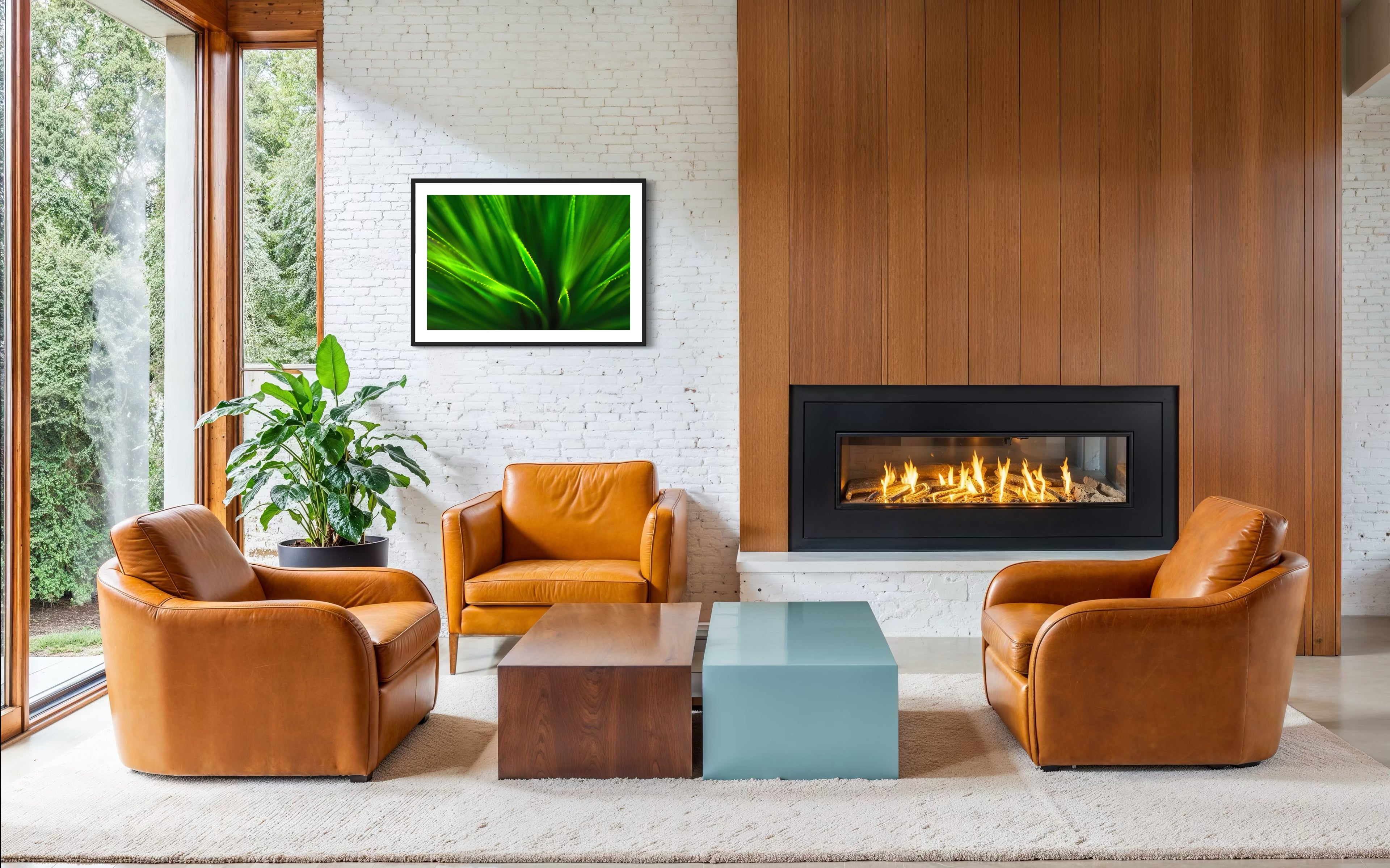 green agave like plant with selective focus in black frame with white matte on white brick wall in modern living room with wide fireplace and three leather chairs