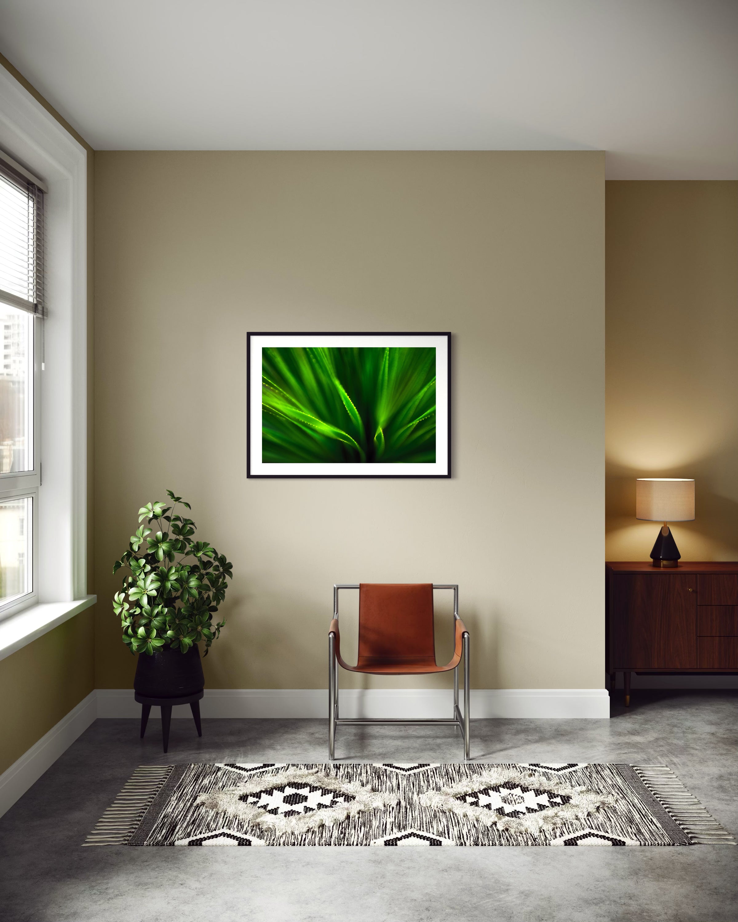 green agave like plant with selective focus in black frame with white matte on tan wall above leather chair on concrete floors in modern sitting area