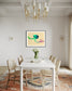 photo of abstract purple, green, blue, yellow wave at the bottom on orange overall in black frame with white matte on white wall in modern dining area 