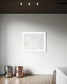 Close up photo of fresh white clean snow in white frame with white matte on white wall in very minimalist area of home with light hardwood floors