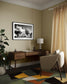 a black and white photo of a building with trees in front in black frame with white matte on tan wall in modern home office with wooden desk, white chair and colorful rung
