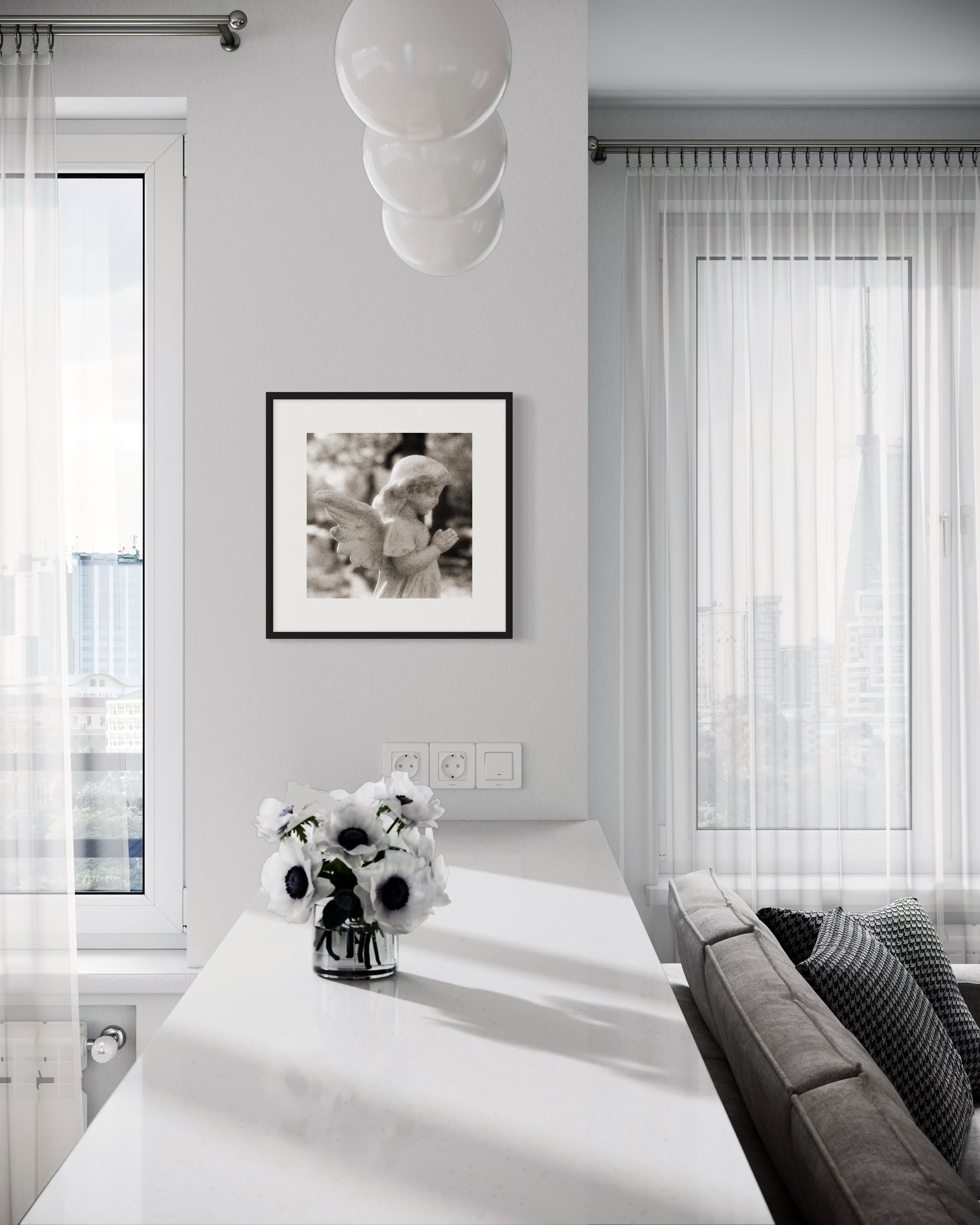 cherub statue with hands in praying position in sepia tone in black frame with white matte on light gray wall in modern living area with white and gray tones