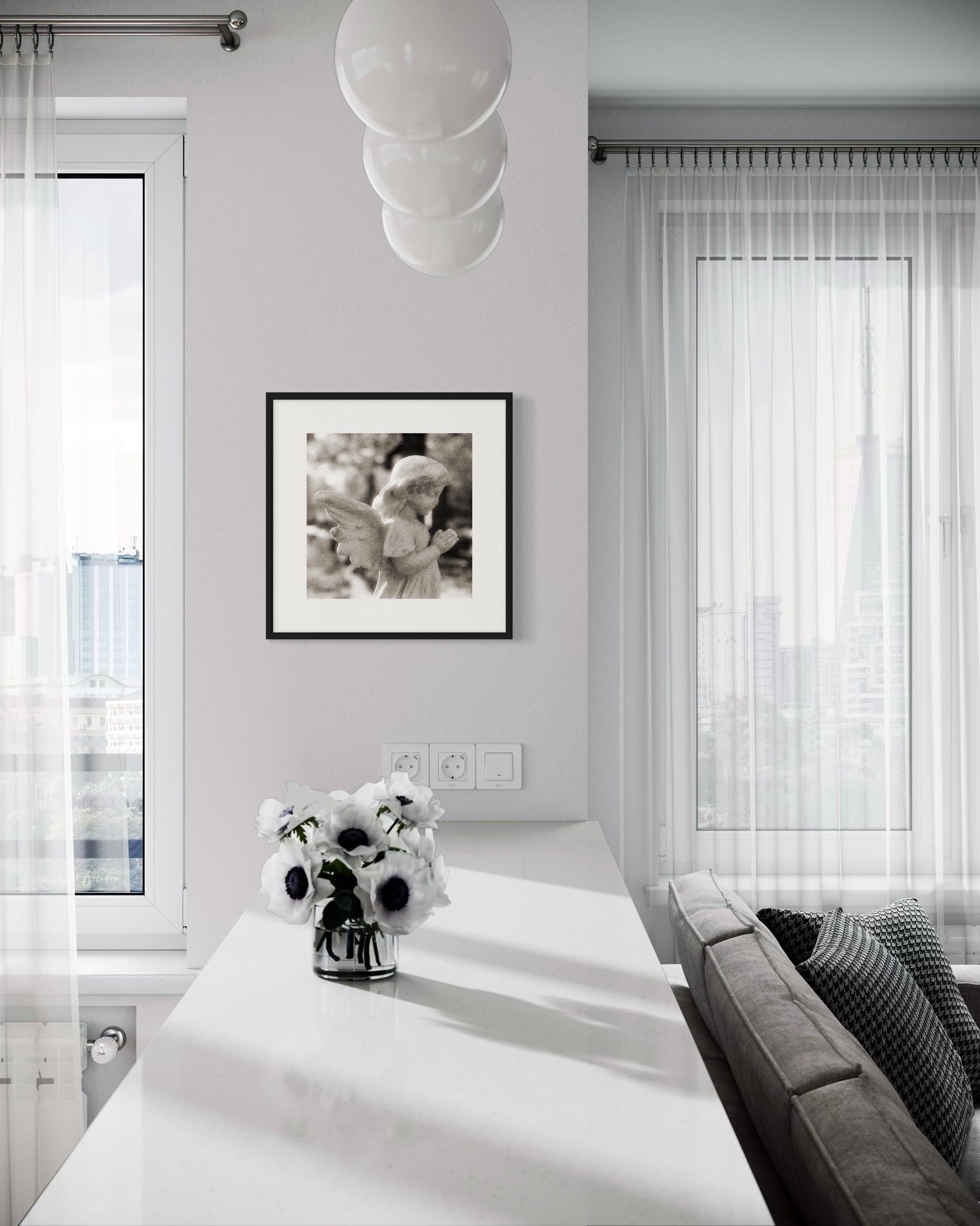 cherub statue with hands in praying position in sepia tone in black frame with white matte on light gray wall in modern living area with white and gray tones