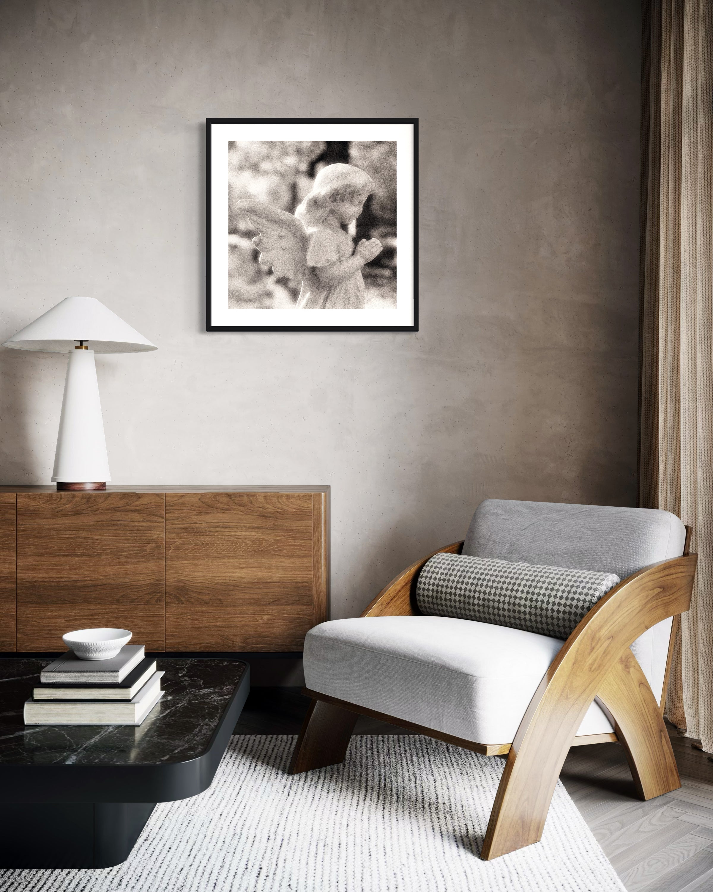 cherub statue with hands in praying position in sepia tone in black frame with white matte on concrete wall modern sitting area with black marble coffee table