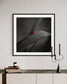 photo of Ladybug in middle of square image, everything except the Ladybug is black and white in black frame on off white wall above rustic wooden furniture