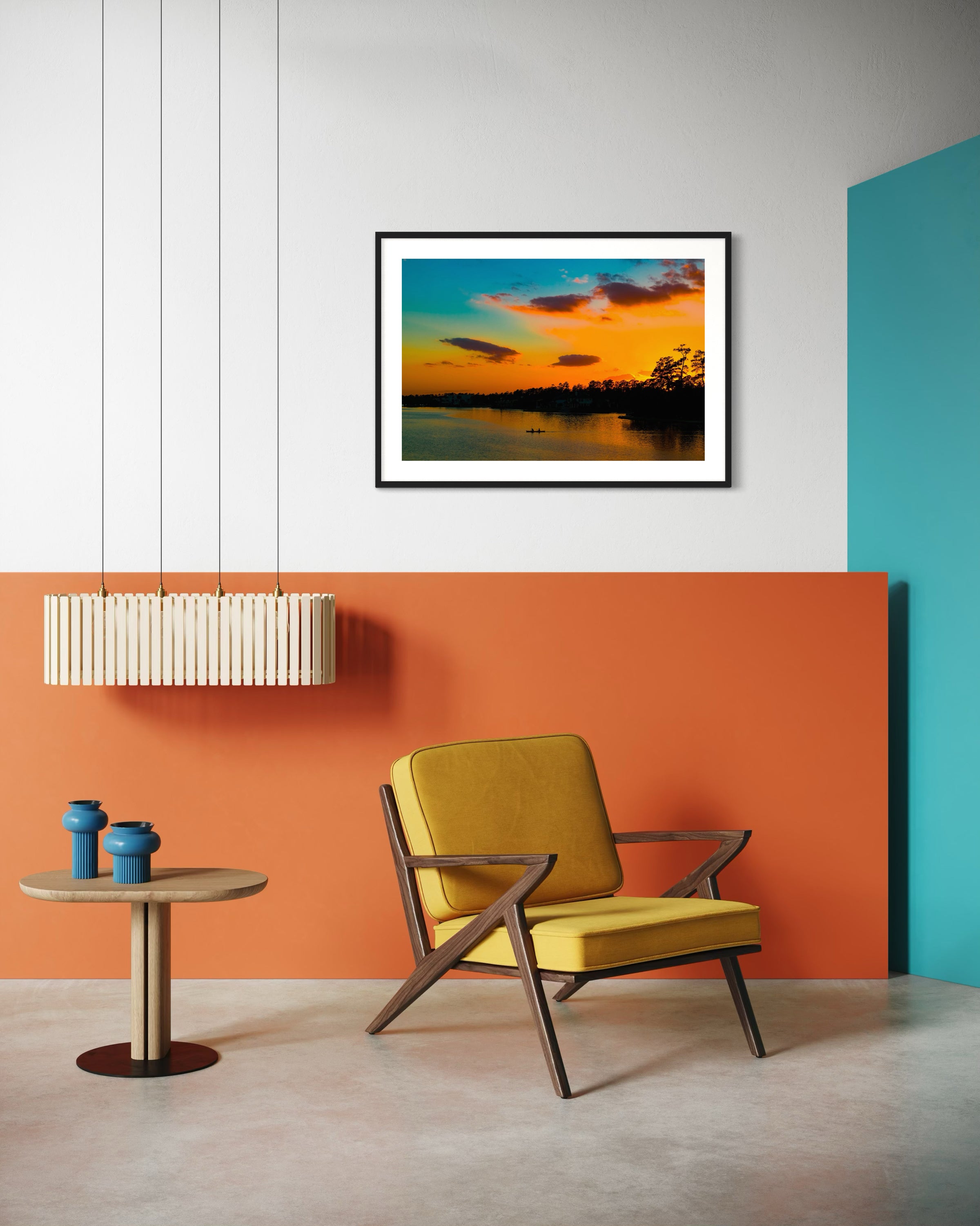 wide angle photo of kayak on lake at sunset in black frame with white matte on white wall in modern sitting area with yellow chair on concrete floors