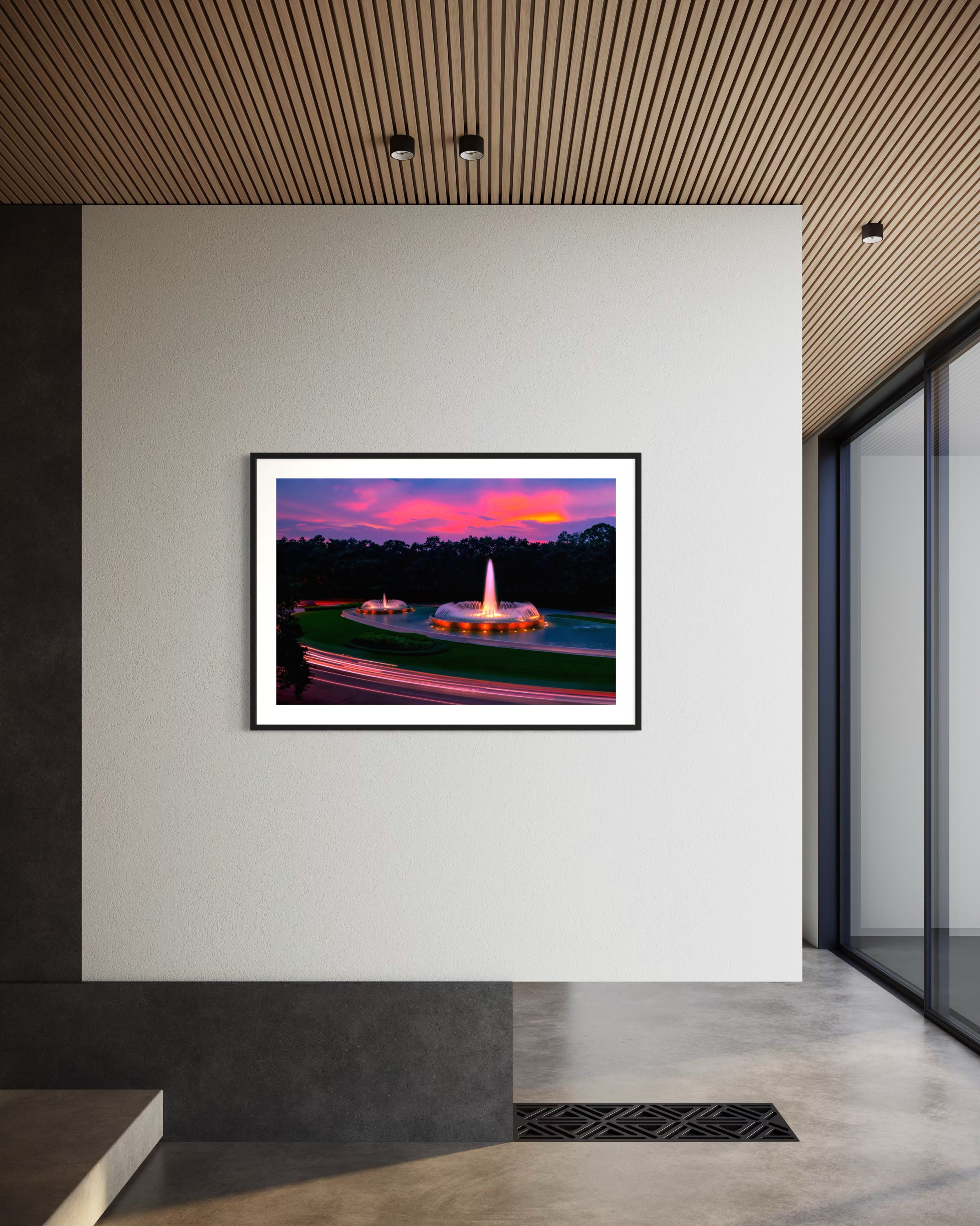 photo of Mecom Fountain in Houston shot at sunset with blurred car lights at the bottom in black frame with white matte on white wall in modern minimalist office with concrete floors