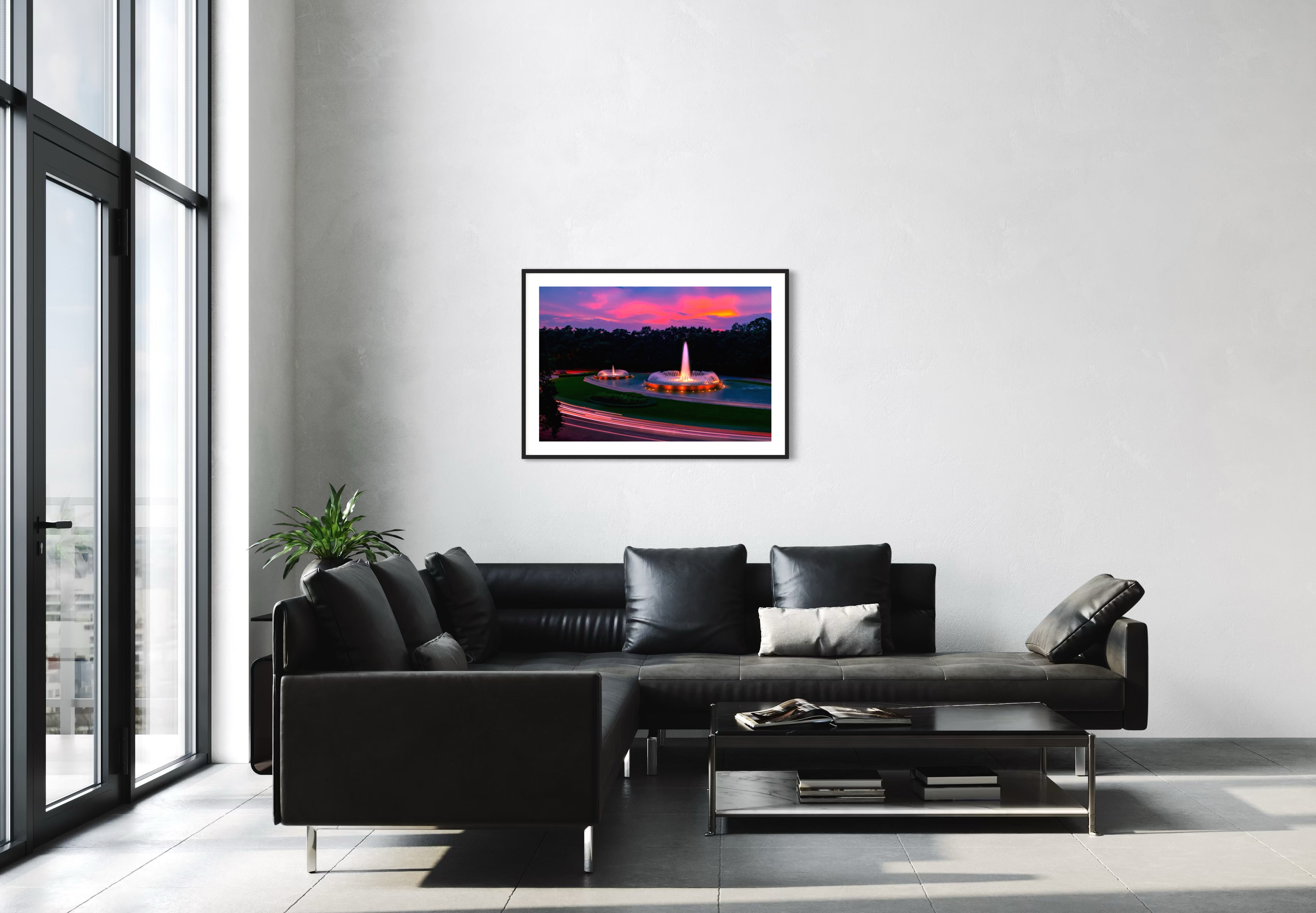 photo of Mecom Fountain in Houston shot at sunset with blurred car lights at the bottom in black frame with white matte on off white wall in modern minimalist living room with black couch and floor to ceiling windows on the left