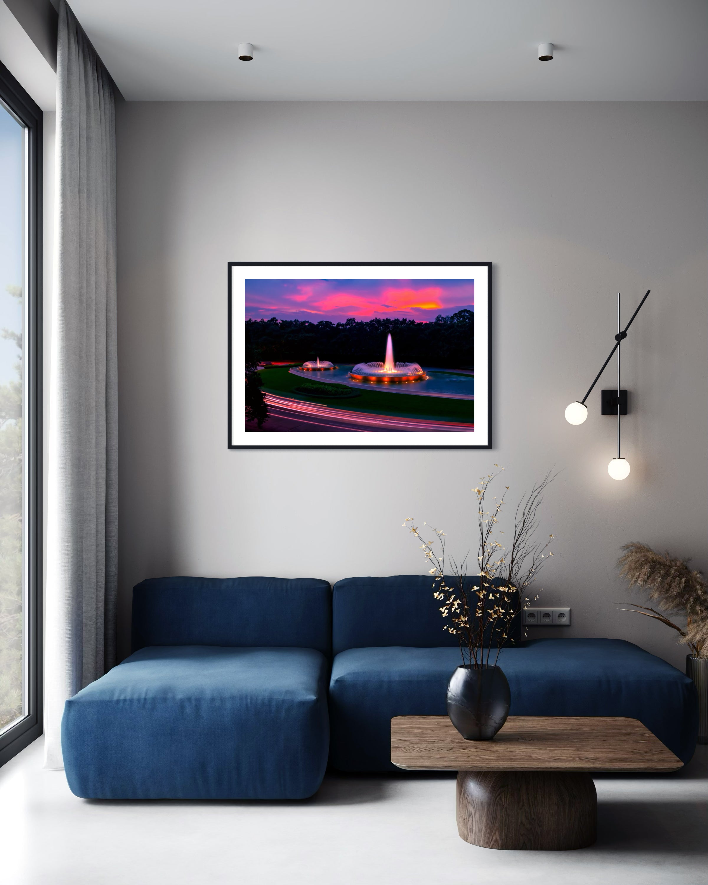 photo of Mecom Fountain in Houston shot at sunset with blurred car lights at the bottom in black frame with white matte on white wall above blue couch in modern yet rustic living room