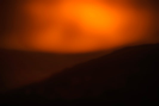photo of orange haze in sky over shallow mountains