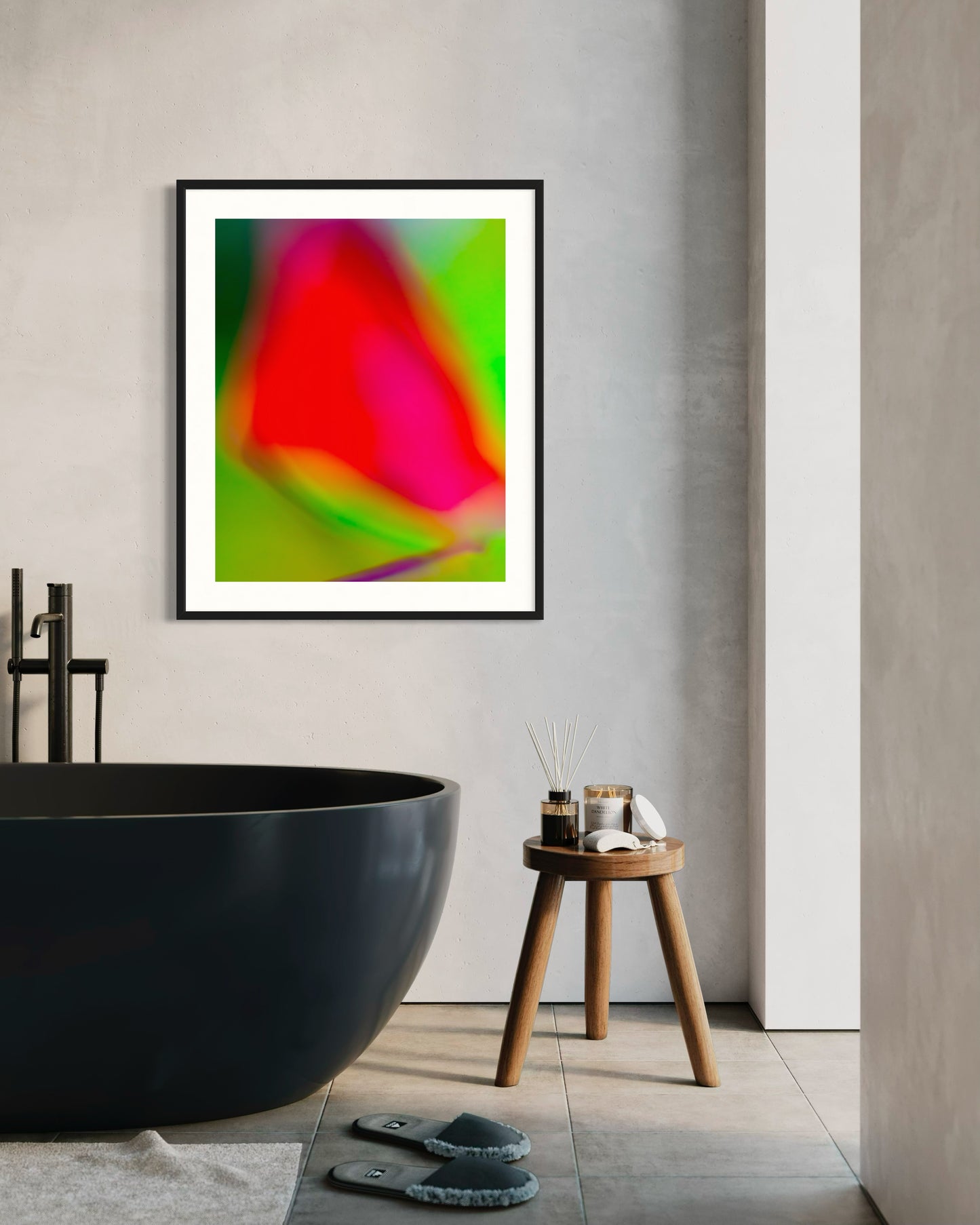 photo of blurry red leaf on blurred bright green background in black frame with white matte on light gray wall above black oval bathtub