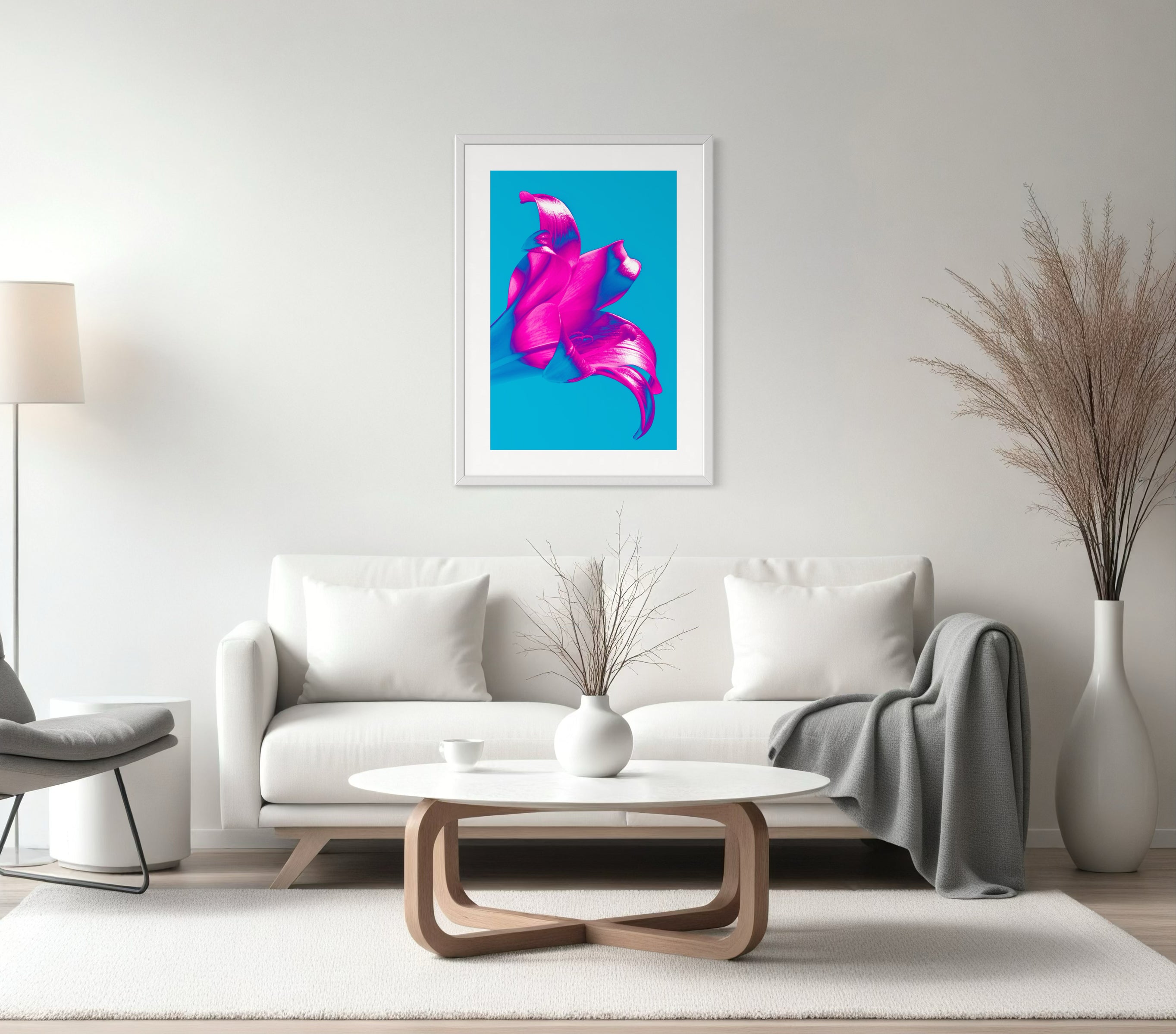bright pop art photo of pink lily on blue background in gray frame with light gray matte above white couch in modern living room with white and light gray tones