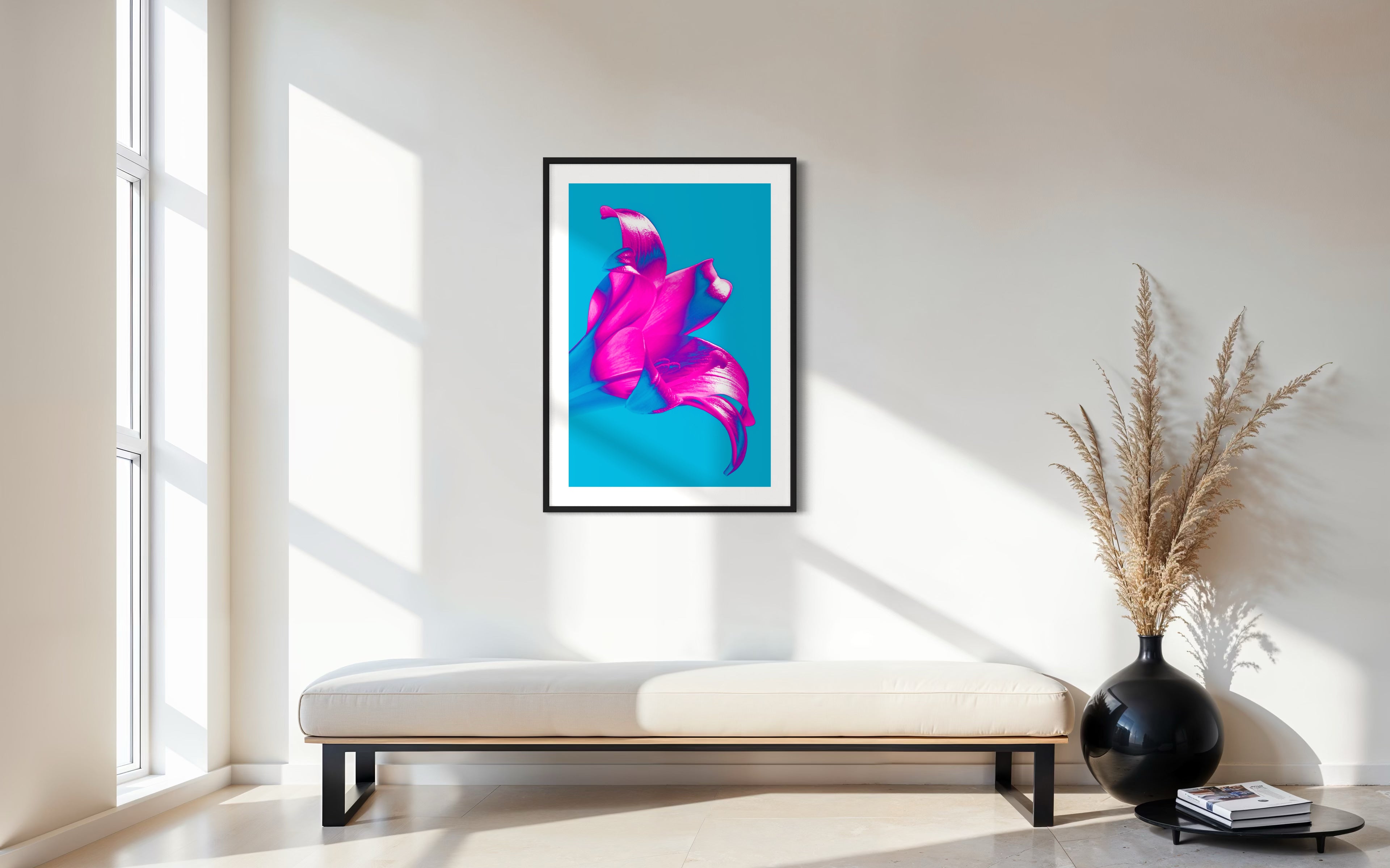 bright pop art photo of pink lily on blue background in black frame with white matte above light tan long bench with cushion  in modern sitting room with white and light tan tones