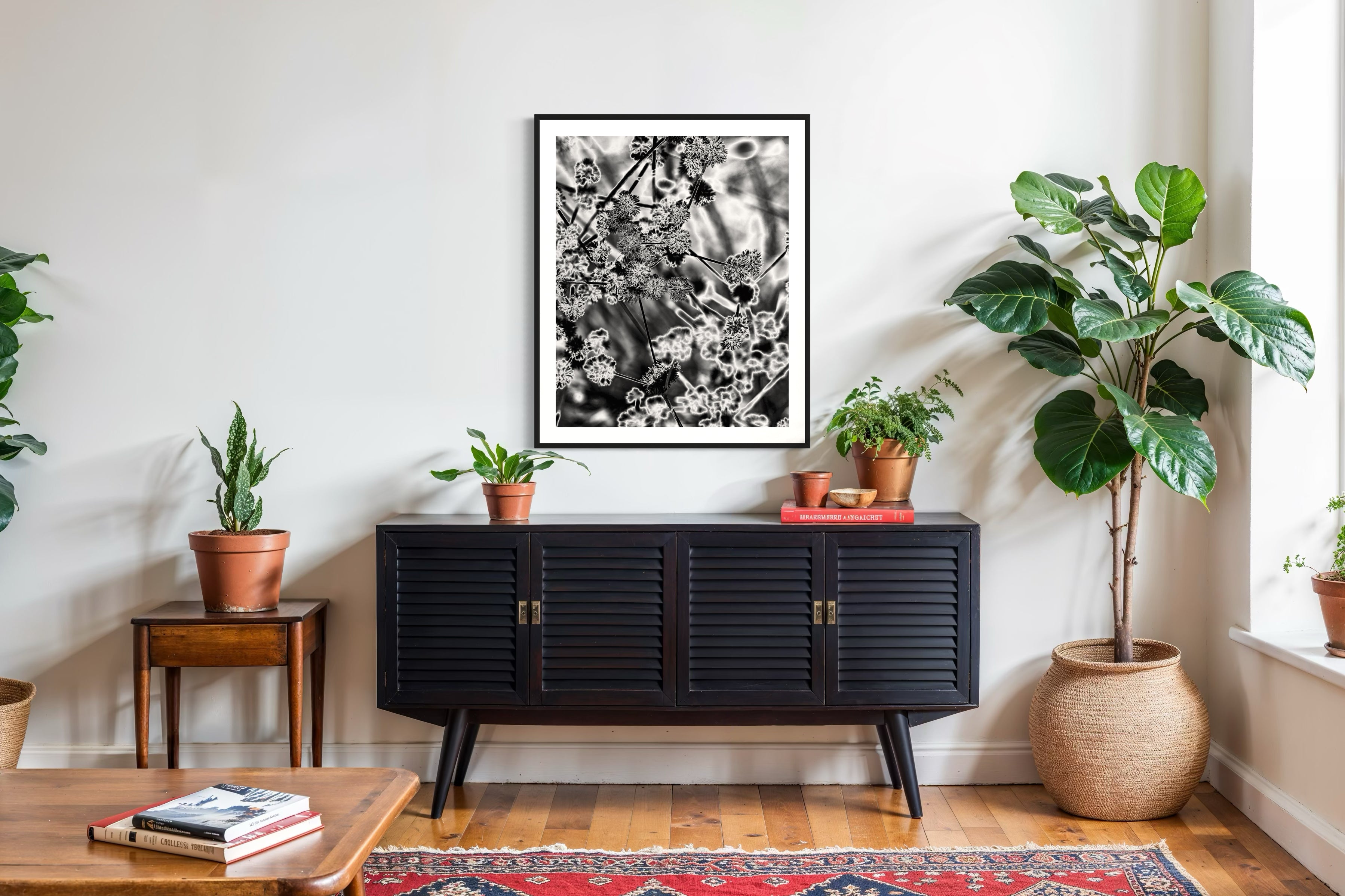 black and white close up of plant with solarized effect in black frame with white matte on white wall above black piece of furniture in country style room
