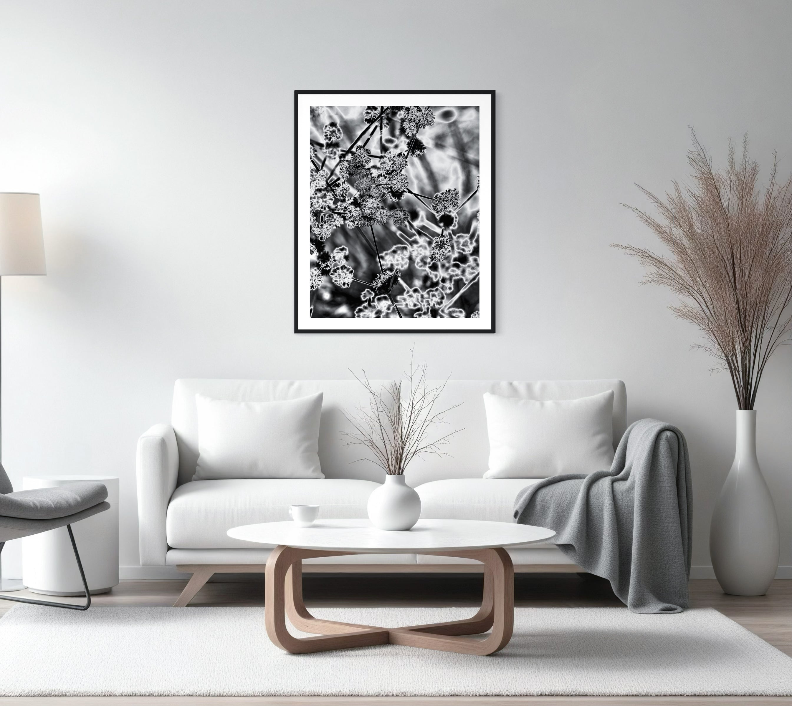 black and white close up of plant with solarized effect in black frame with white matte above white couch in modern minimalist living room with white and light gray tones