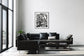 black and white close up of plant with solarized effect in black frame with white matte on white wall in minimalist modern space with concrete floors and floor to ceiling windows on the left and black couch