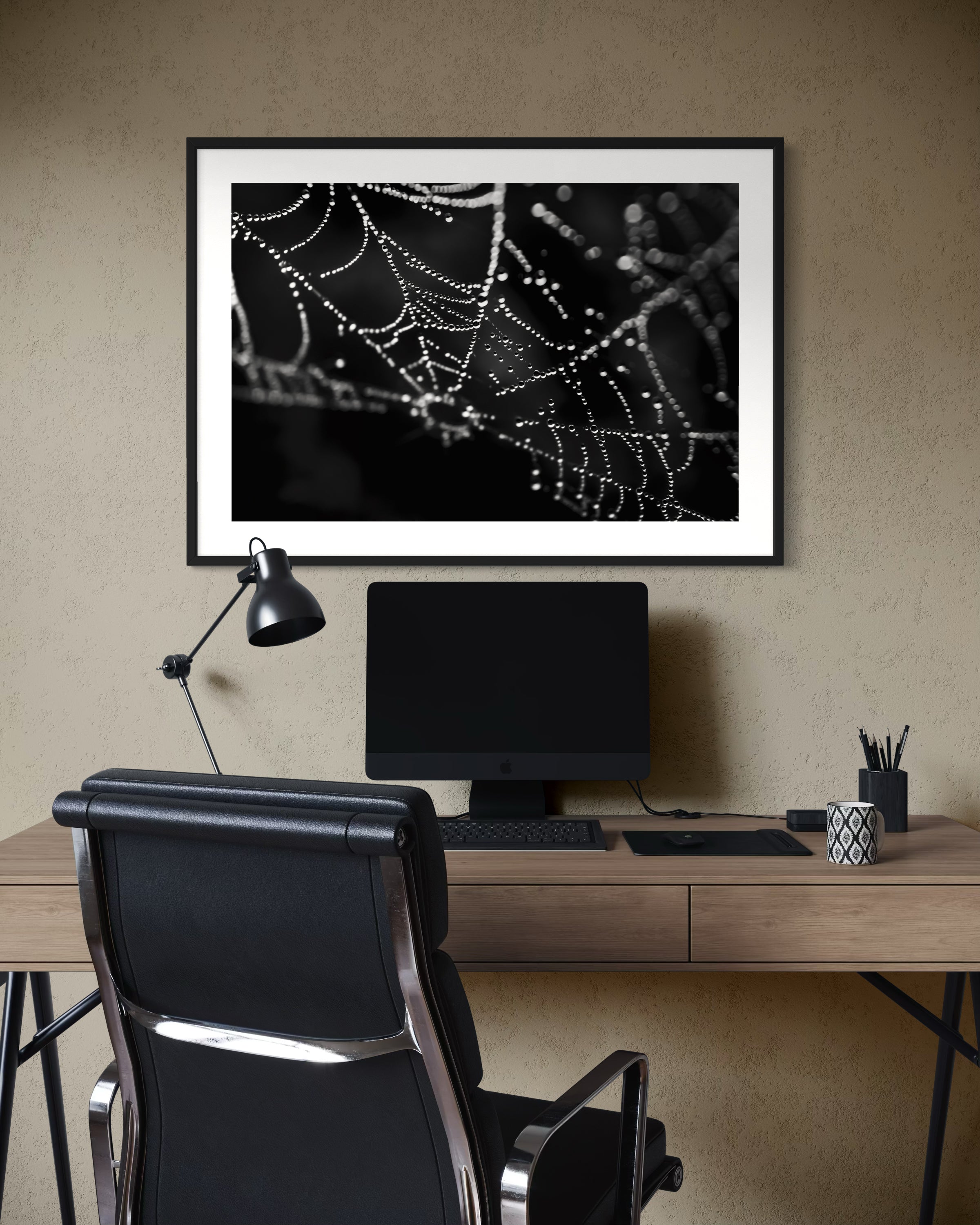 close up photo of rain drops on spider web in black and white in black frame with white matte on tan wall in modern home office