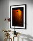 photo of sailboat sailing at sunset, in a very warm tone in black frame on white wall with three small golden tables below