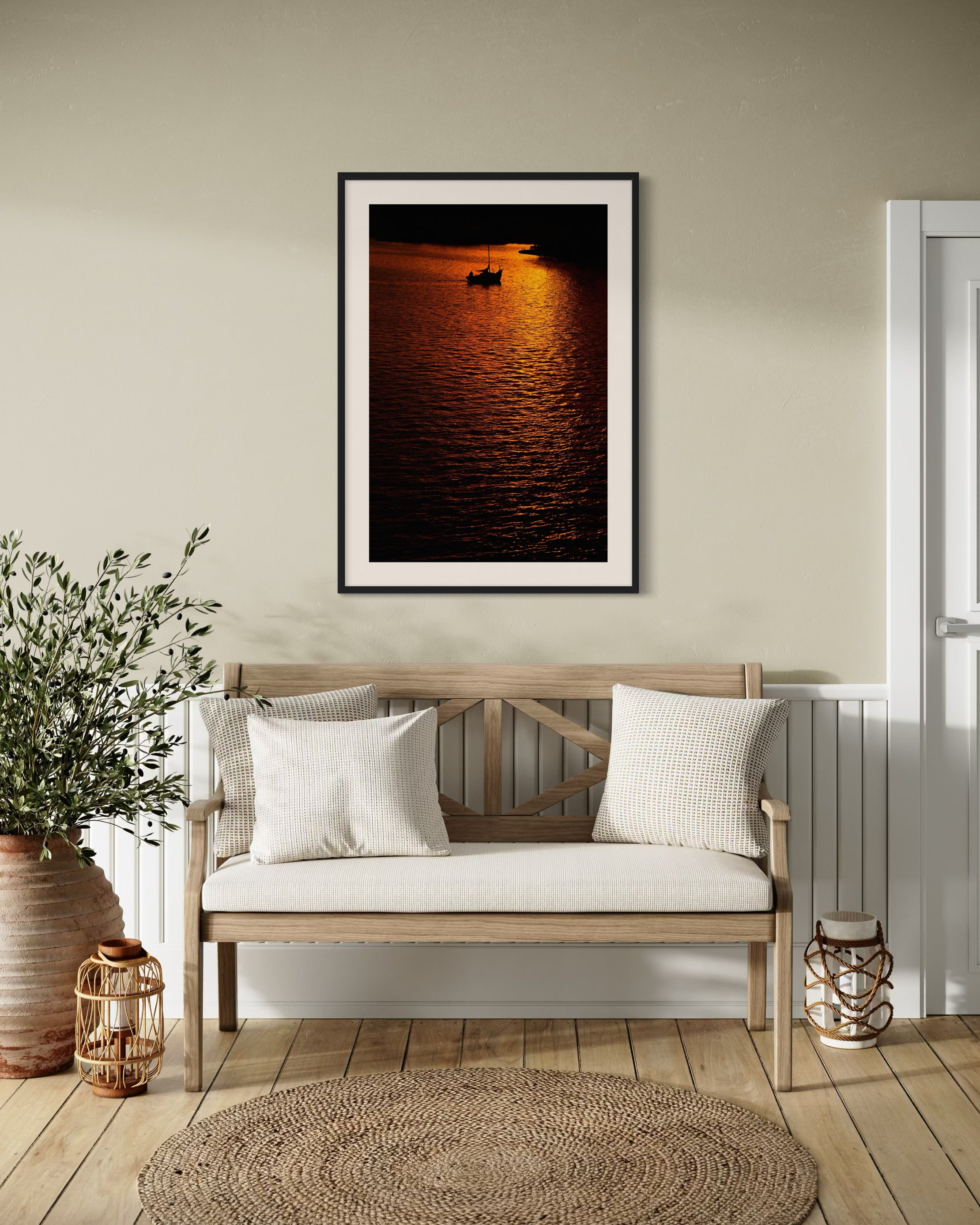 photo of sailboat sailing at sunset, in a very warm tone in black frame with white matte on tan wall in coastal style sitting area