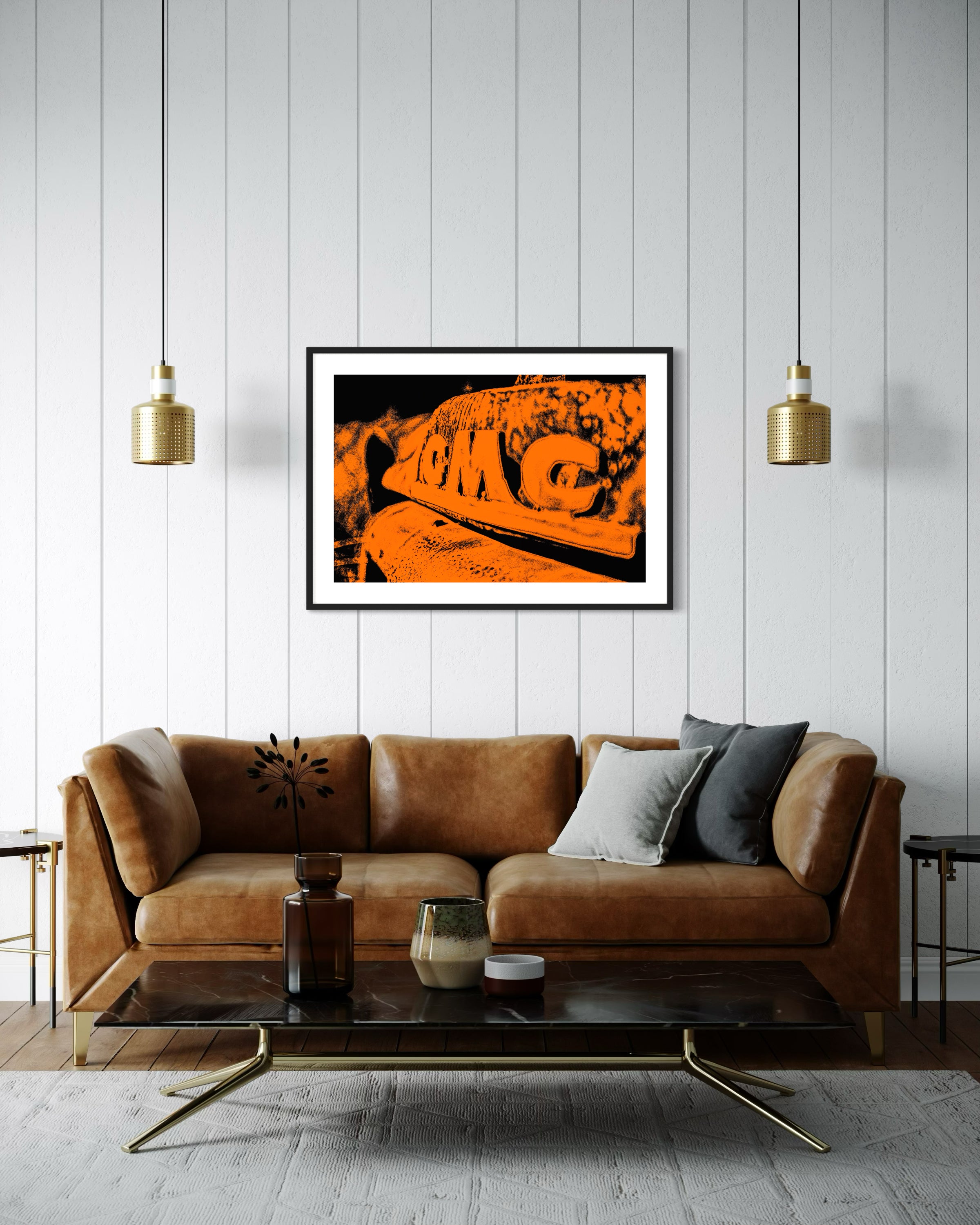 orange tone photo of front of old truck grill in black frame with white matte on off white wall in living room with brown leather couch and black marble top coffee table