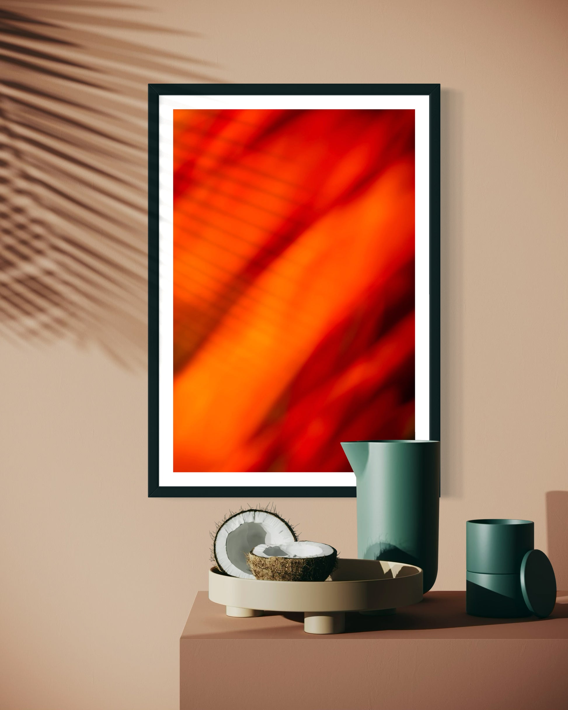 orange abstract with upward motion in black frame with white matte on tan wall with palm tree shadow on part of the print above table