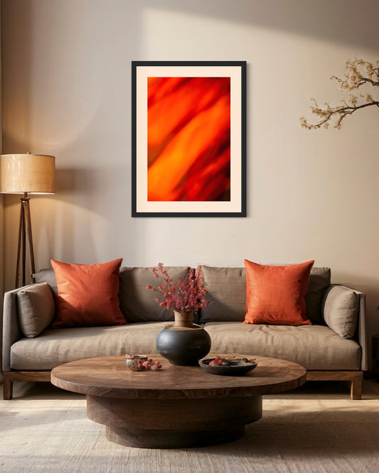 orange abstract with upward motion in black frame with light tan matte on wall above couch in room with warm tones