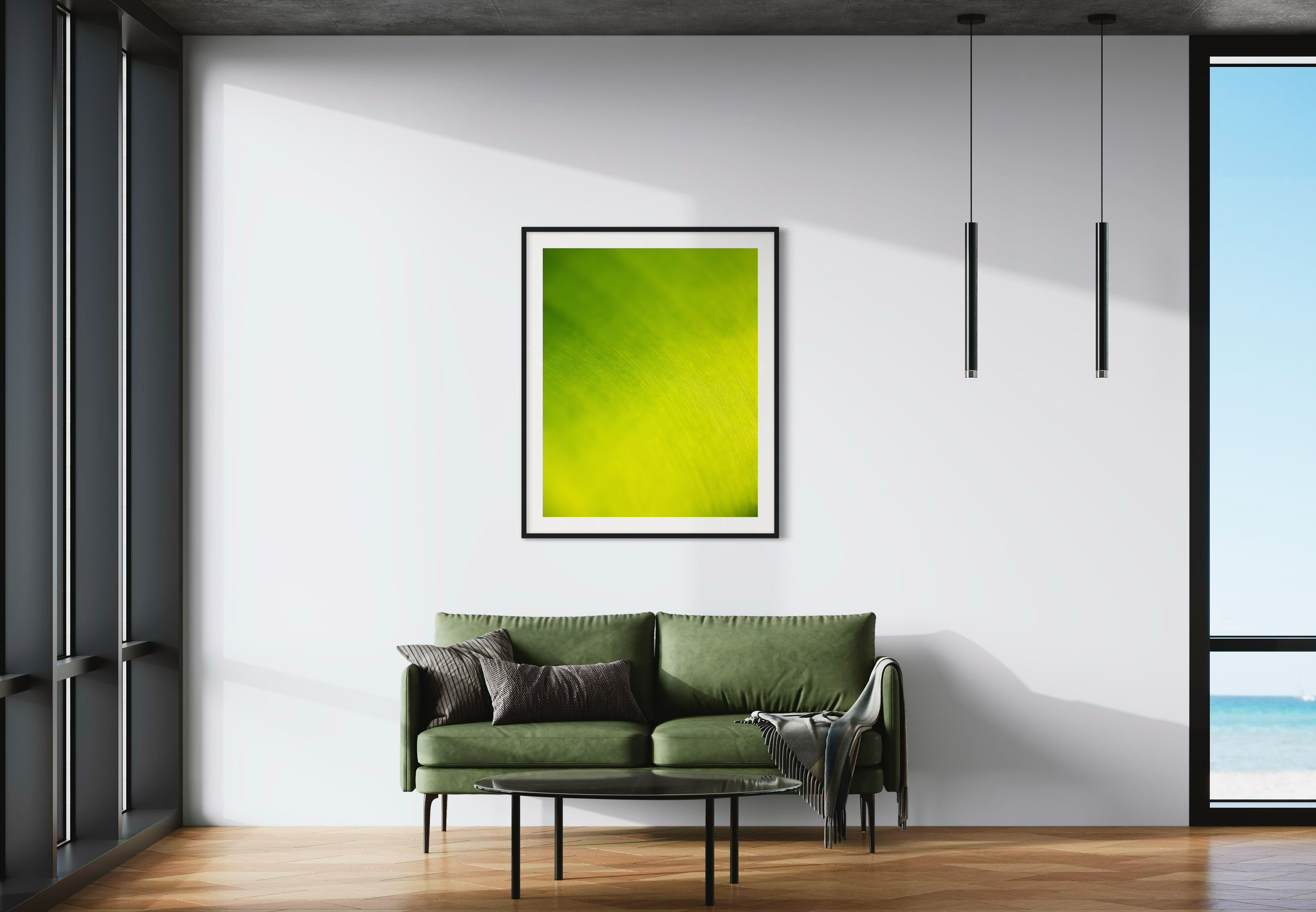 close up of large tropical leaf with the lines flowing like a waterfall in black frame with off white matte on white wall wall in minimalist living room with small green couch