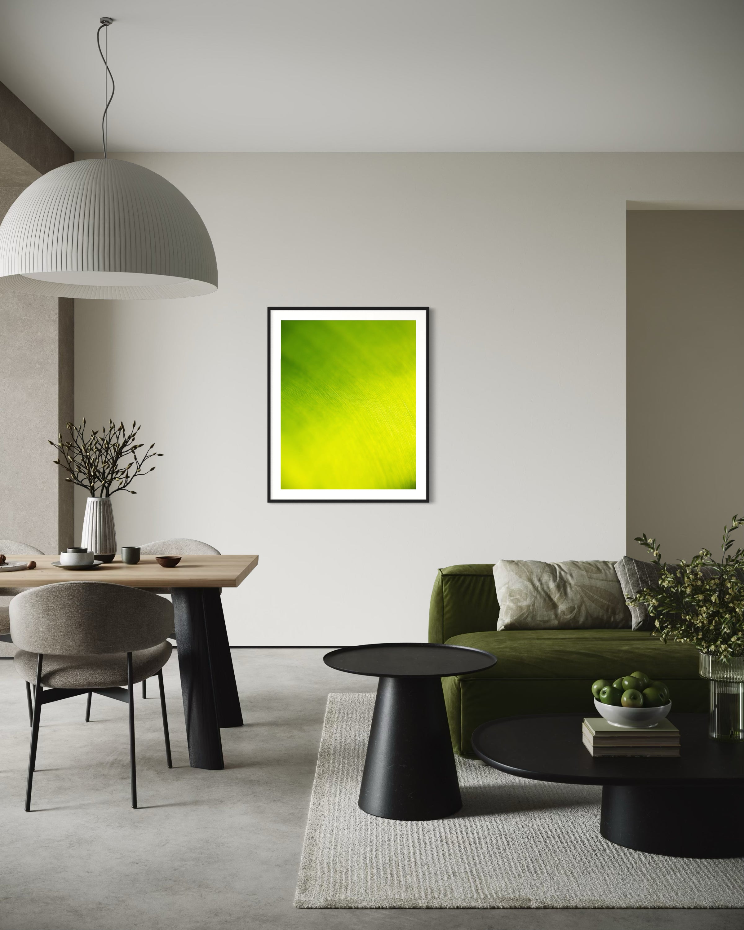 close up of large tropical leaf with the lines flowing like a waterfall in black frame with white matte on light gray wall in modern living room with green couch, white rug and concrete floors