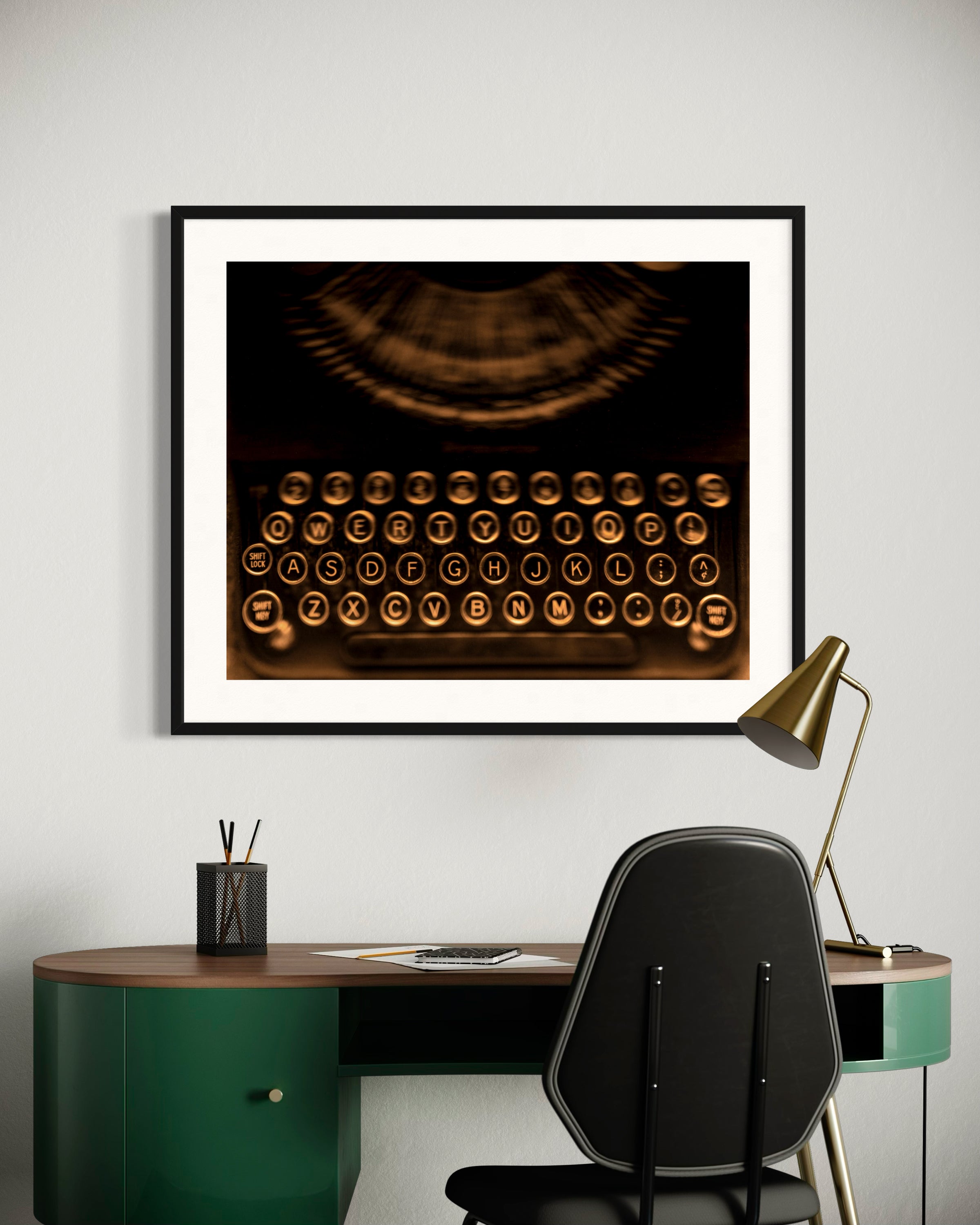 close up of old typewriter from above, horizontal black and white photo in black frame with white matte on wall above small green modern desk