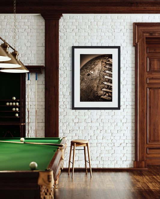 Sepia tone old football close up with a grungy look shot in studio in black frame on white brick wall in gameroom