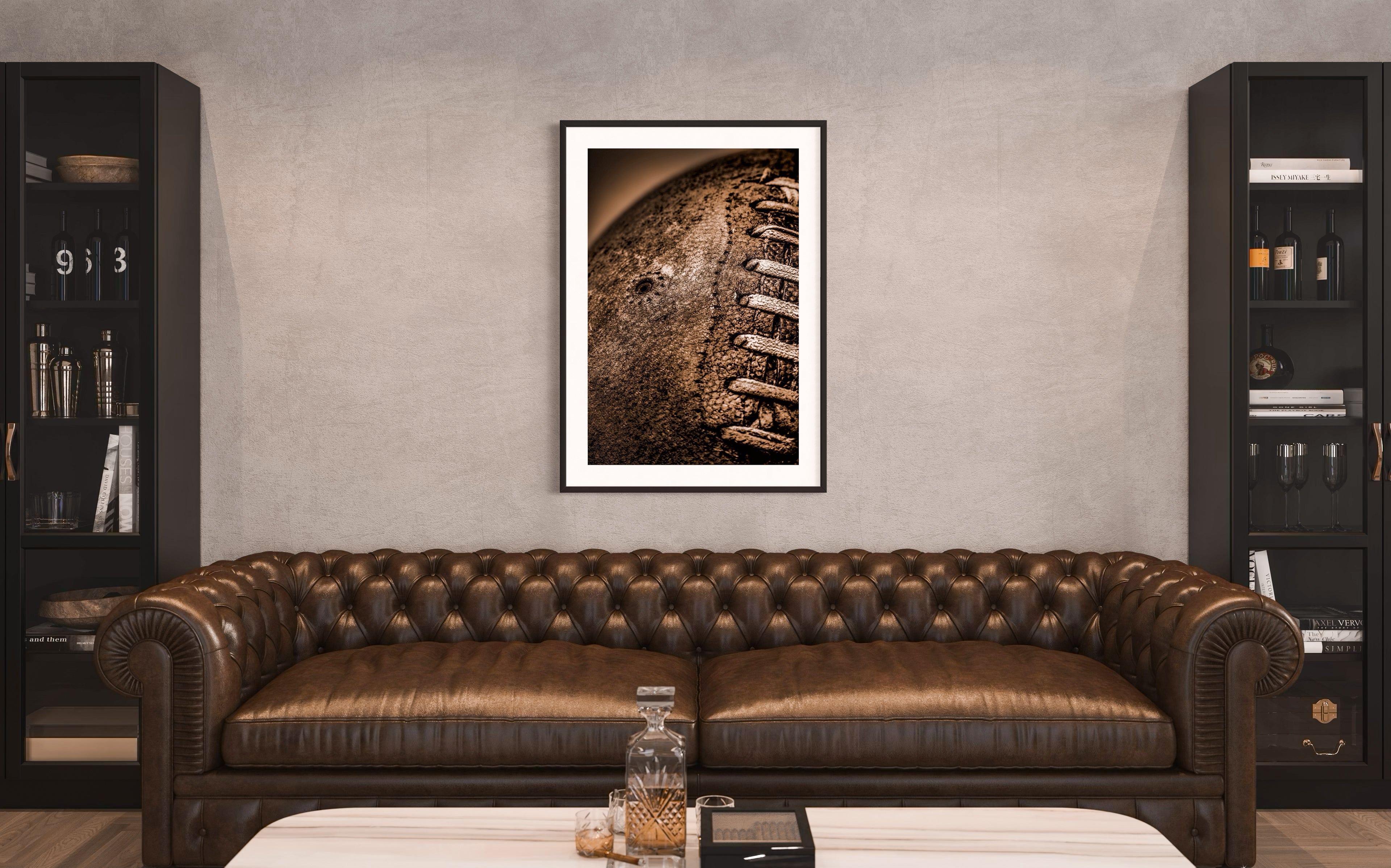 Sepia tone old football close up with a grungy look shot in studio in black frame with white matte on light gray wall above leather couch in bar area in a home
