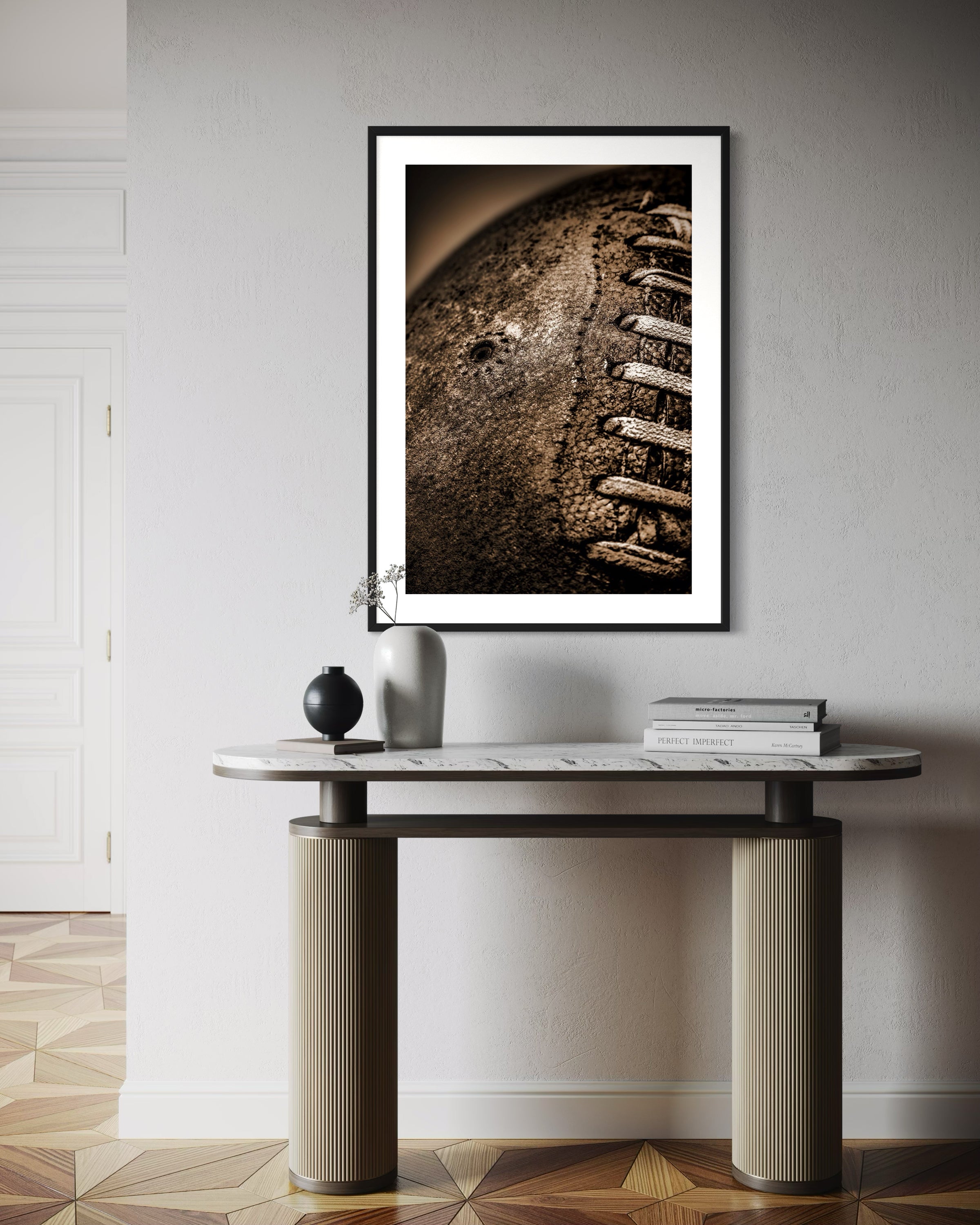 Sepia tone old football close up with a grungy look shot in studio in black frame with white matte on white wall above small modern table