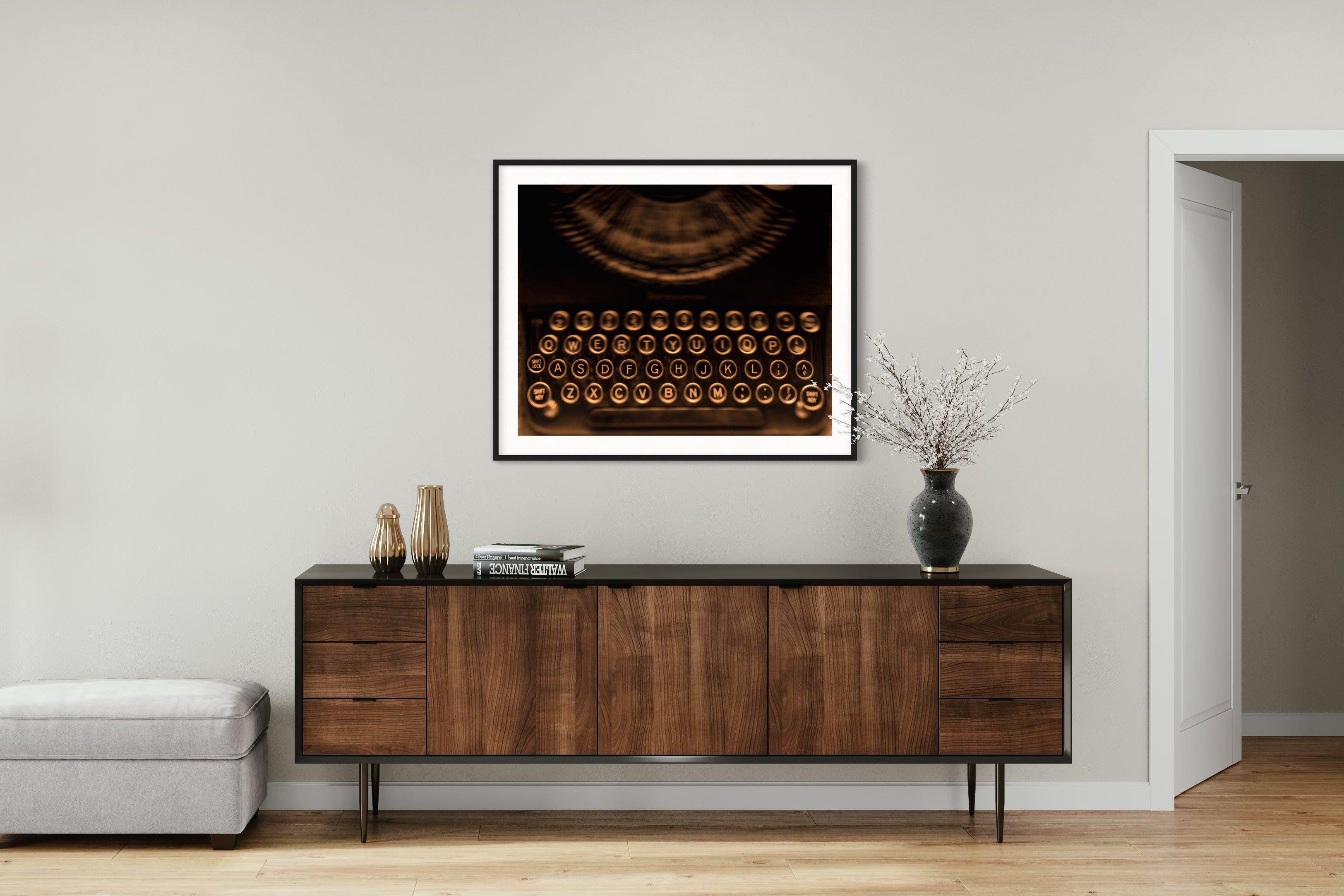 close up of old typewriter from above, horizontal black and white photo in black frame with white matte on wall above wide wooden table in minimalist room